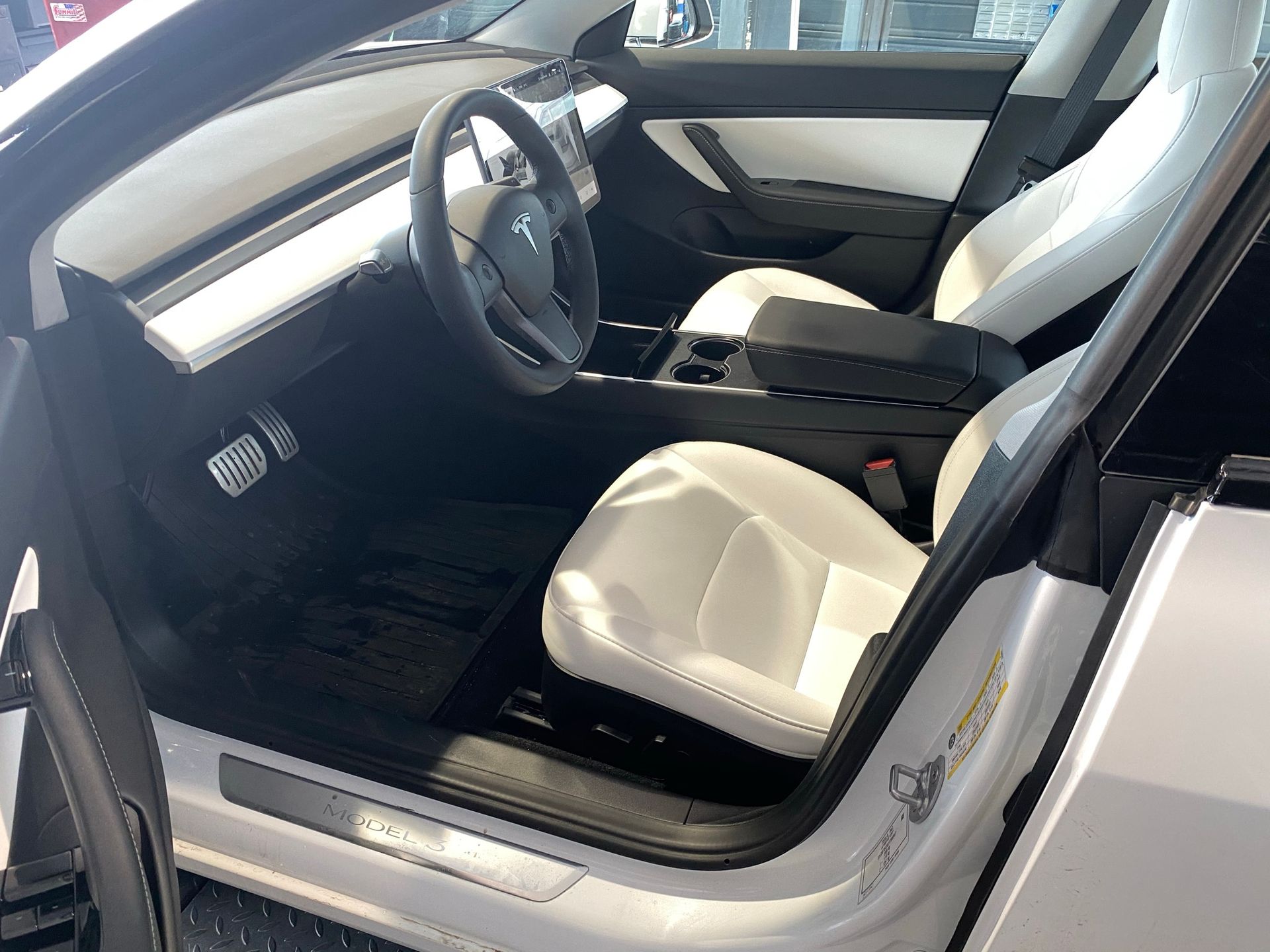 L'intérieur d'une Tesla modèle 3 blanche avec la porte ouverte.