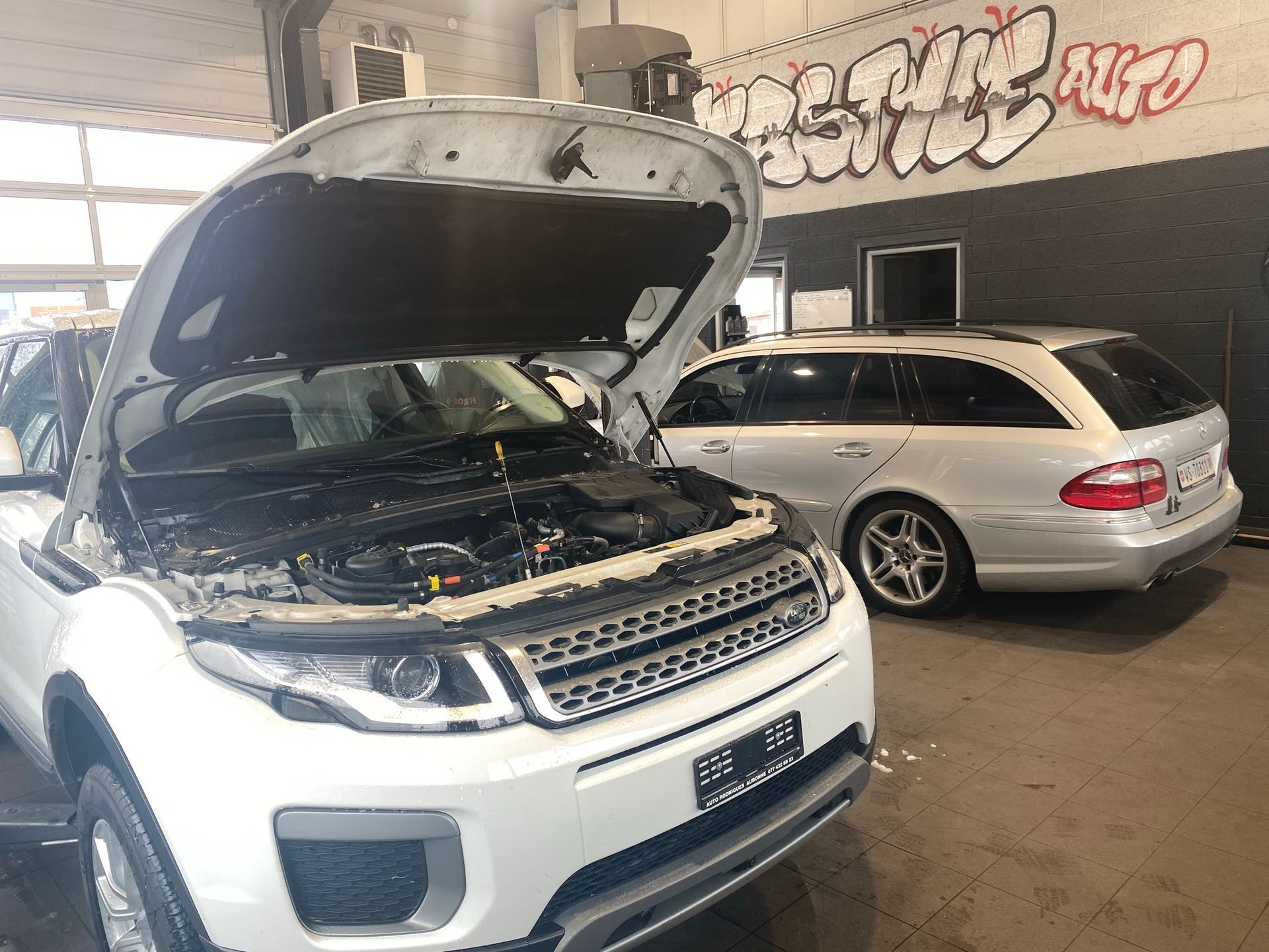 Deux voitures sont garées dans un garage avec le capot ouvert.
