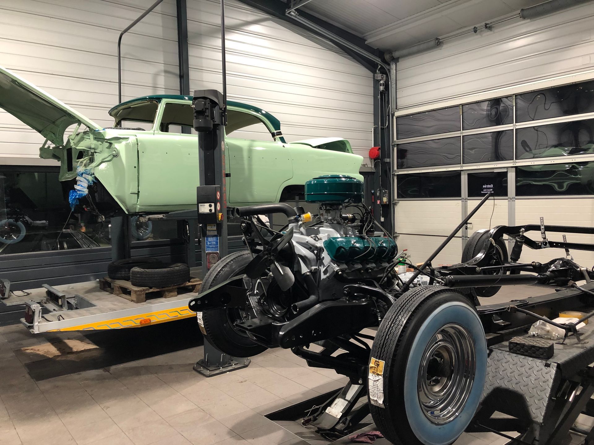 Un camion vert est assis dans un garage à côté d’une moto.