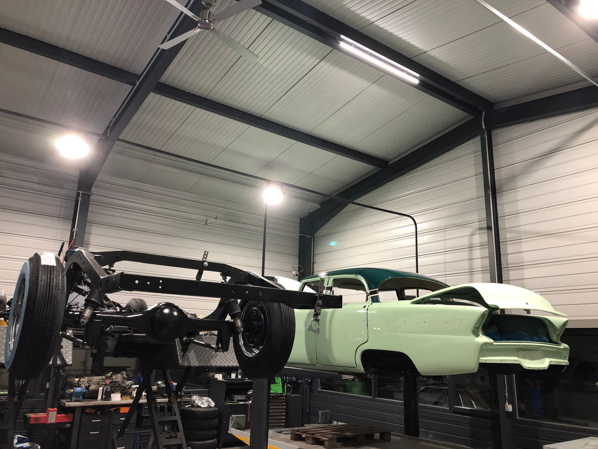 Une voiture verte est assise sur un ascenseur dans un garage.