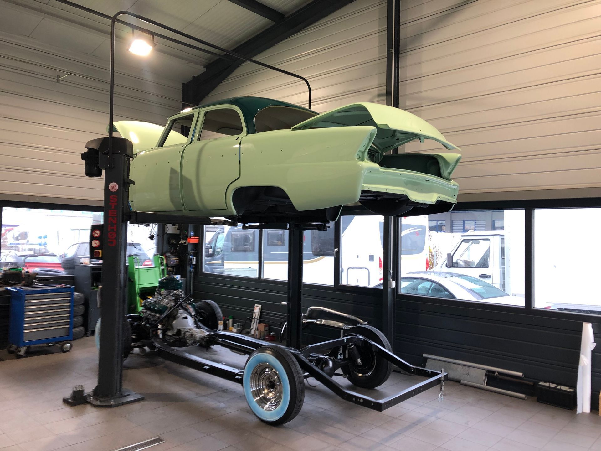Une voiture verte est assise sur un ascenseur dans un garage.