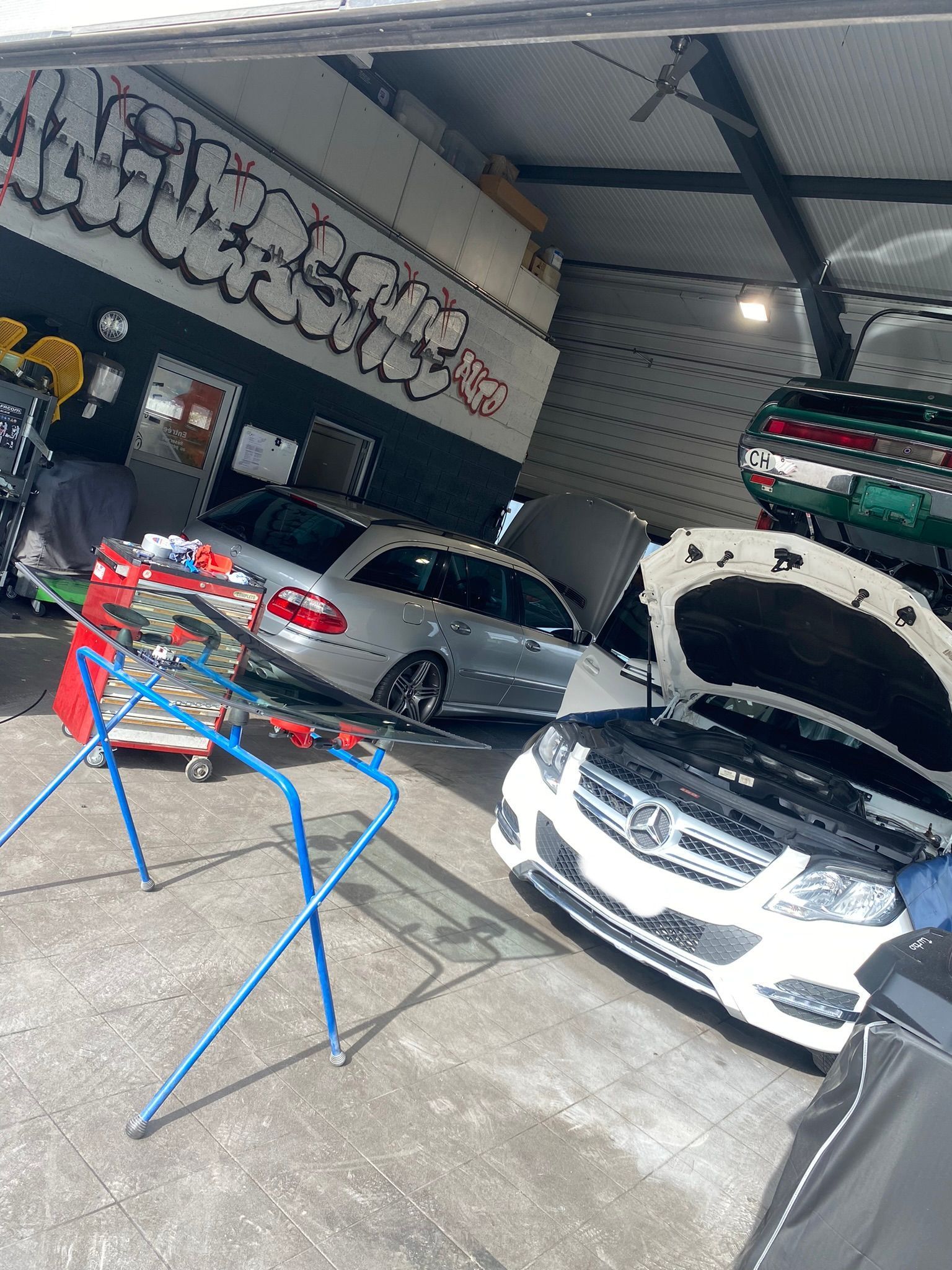 Une rangée de voitures sont garées dans un garage, le capot ouvert.