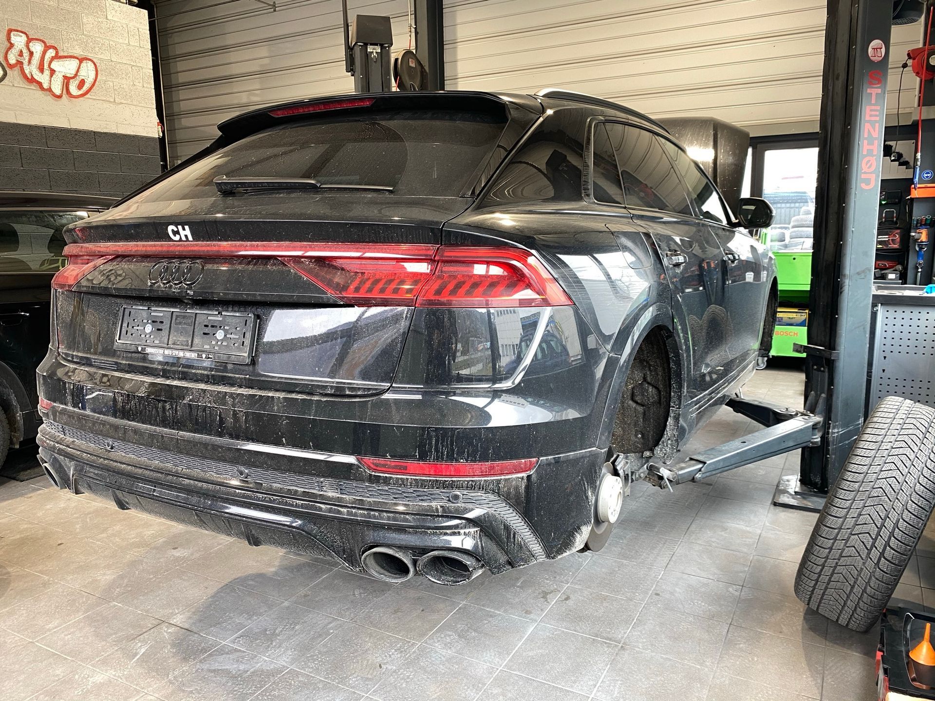 Une Audi Q8 noire est assise sur un ascenseur dans un garage.