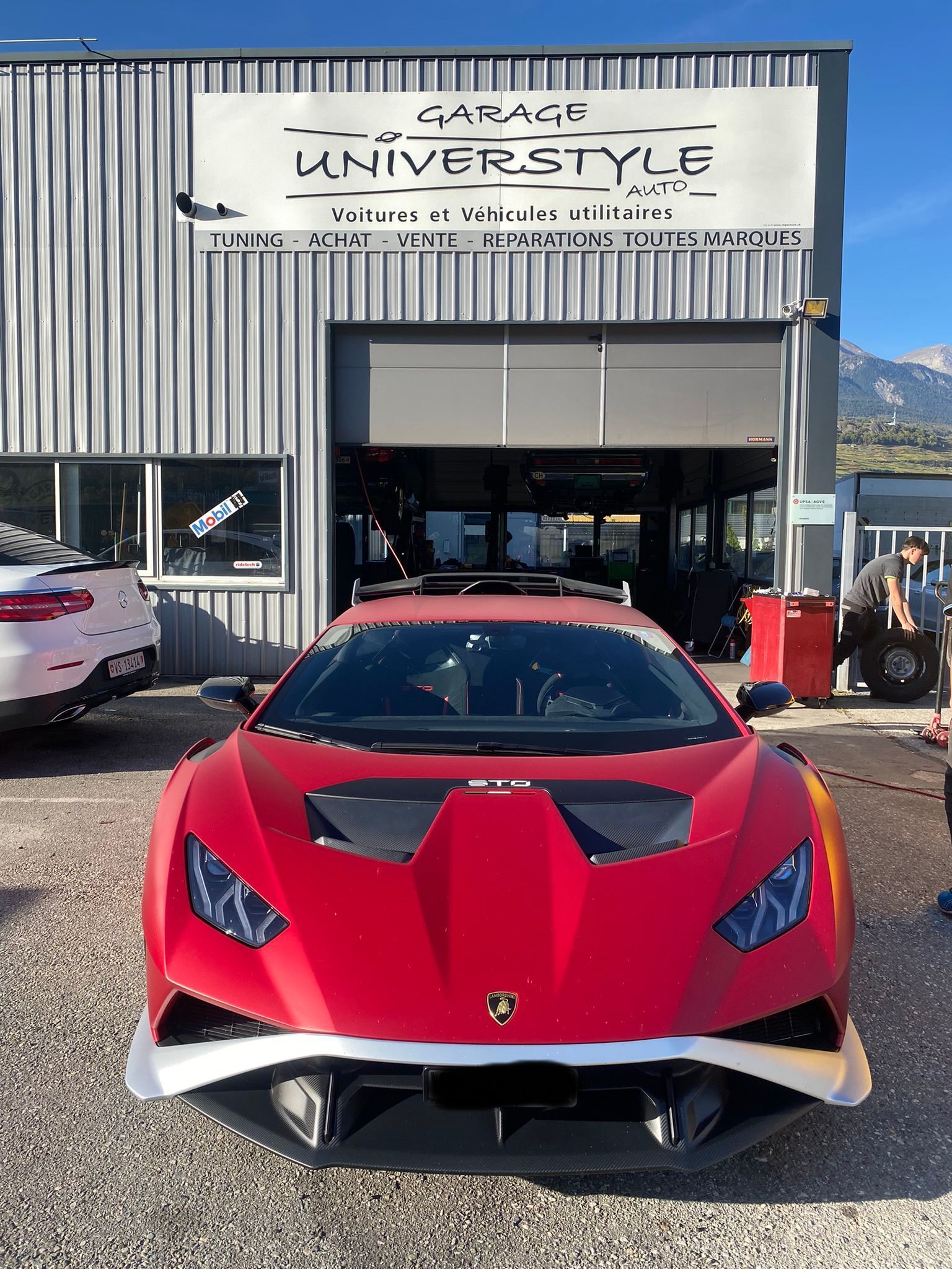 Une voiture de sport rouge est garée devant un garage.