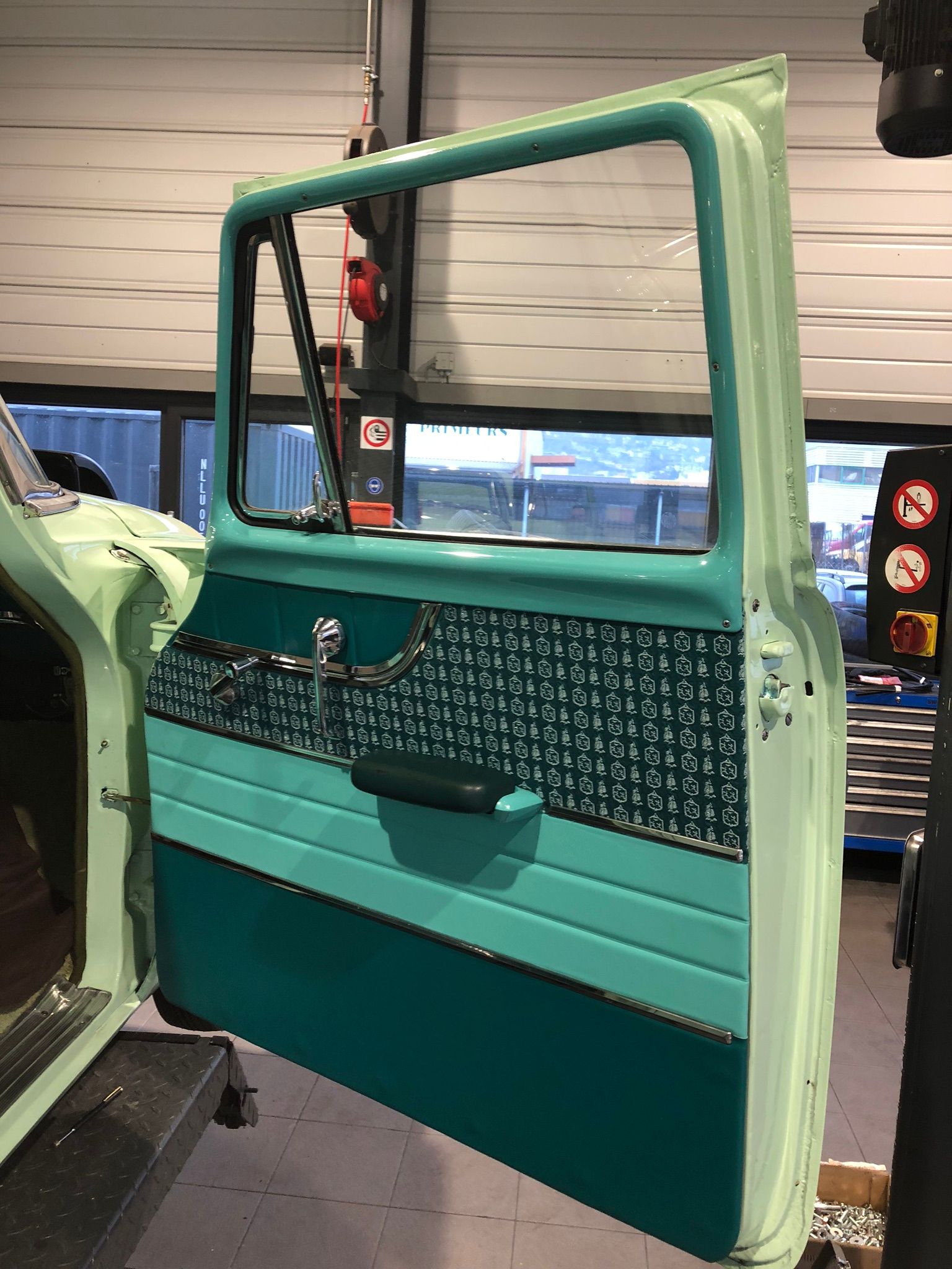 Une portière de voiture avec une bordure verte est ouverte dans un garage.