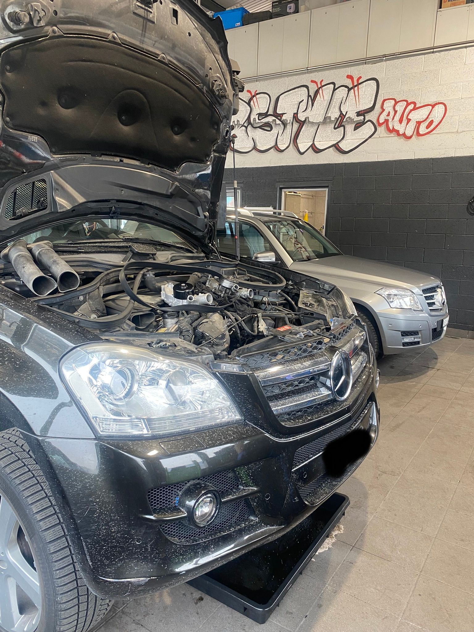 Une voiture avec son capot ouvert se trouve dans un garage.