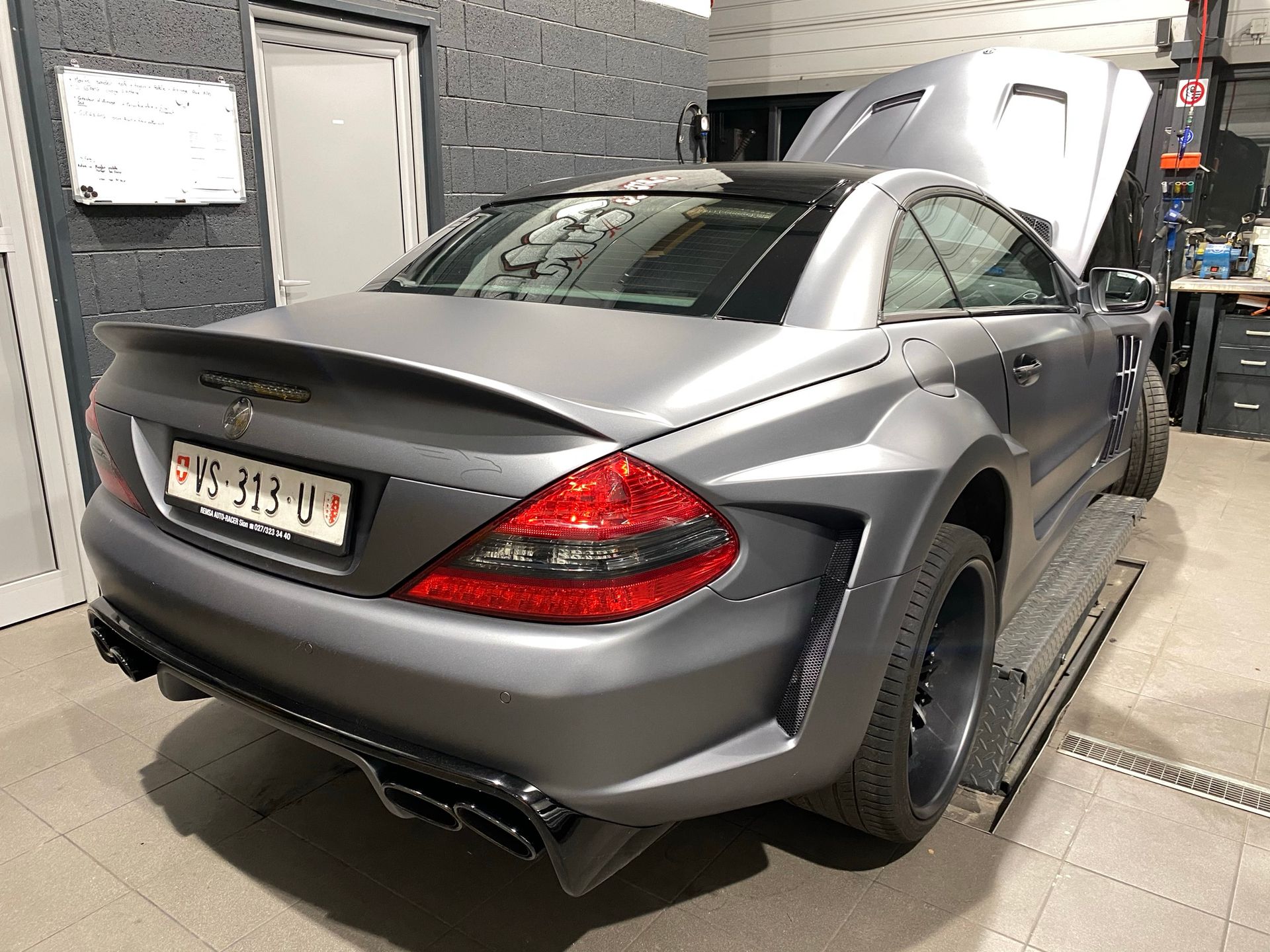 Une Mercedes SL63 AMG est garée dans un garage avec son capot ouvert.
