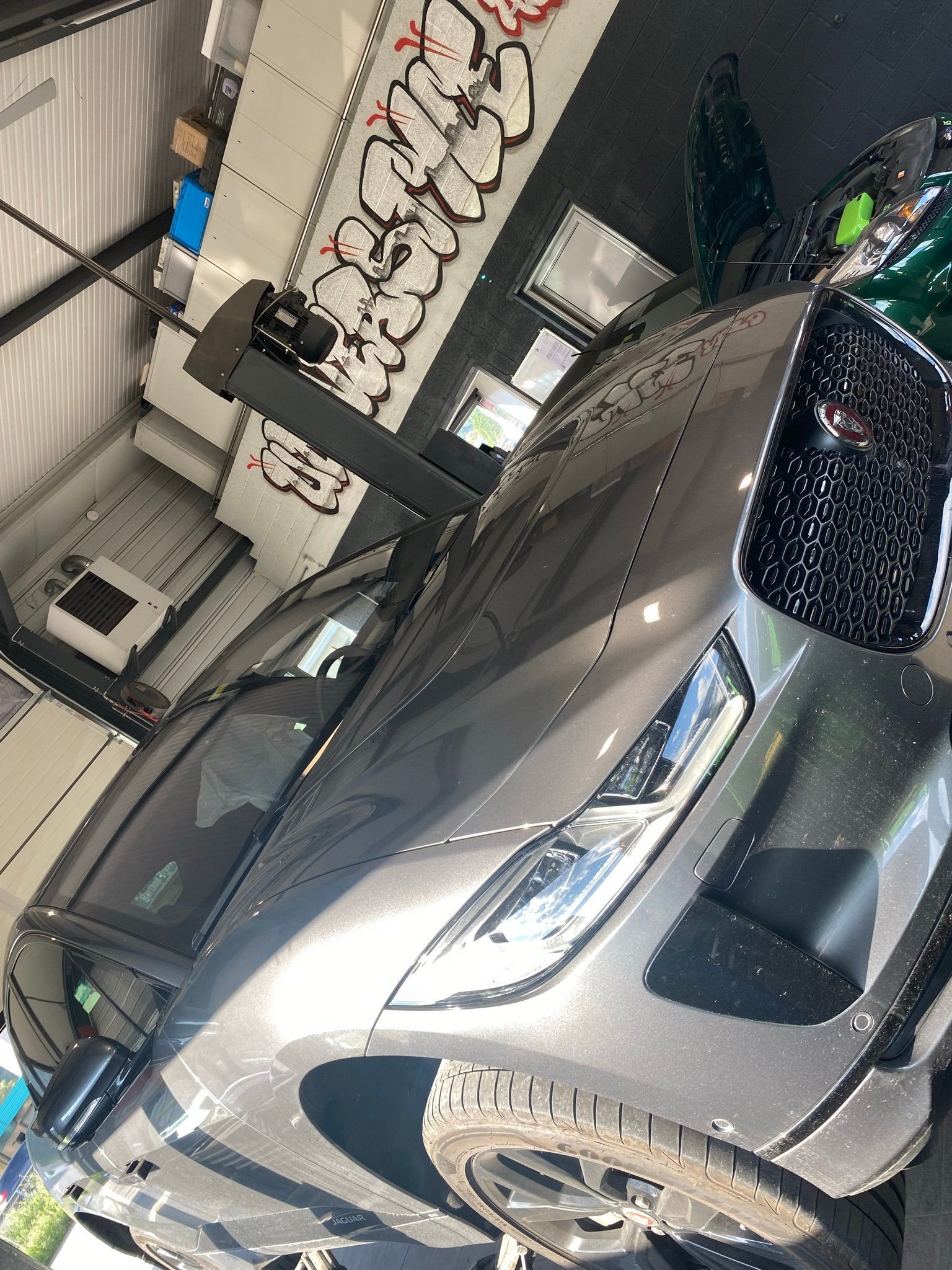 Une voiture est garée dans un garage avec des graffitis sur le mur derrière elle.