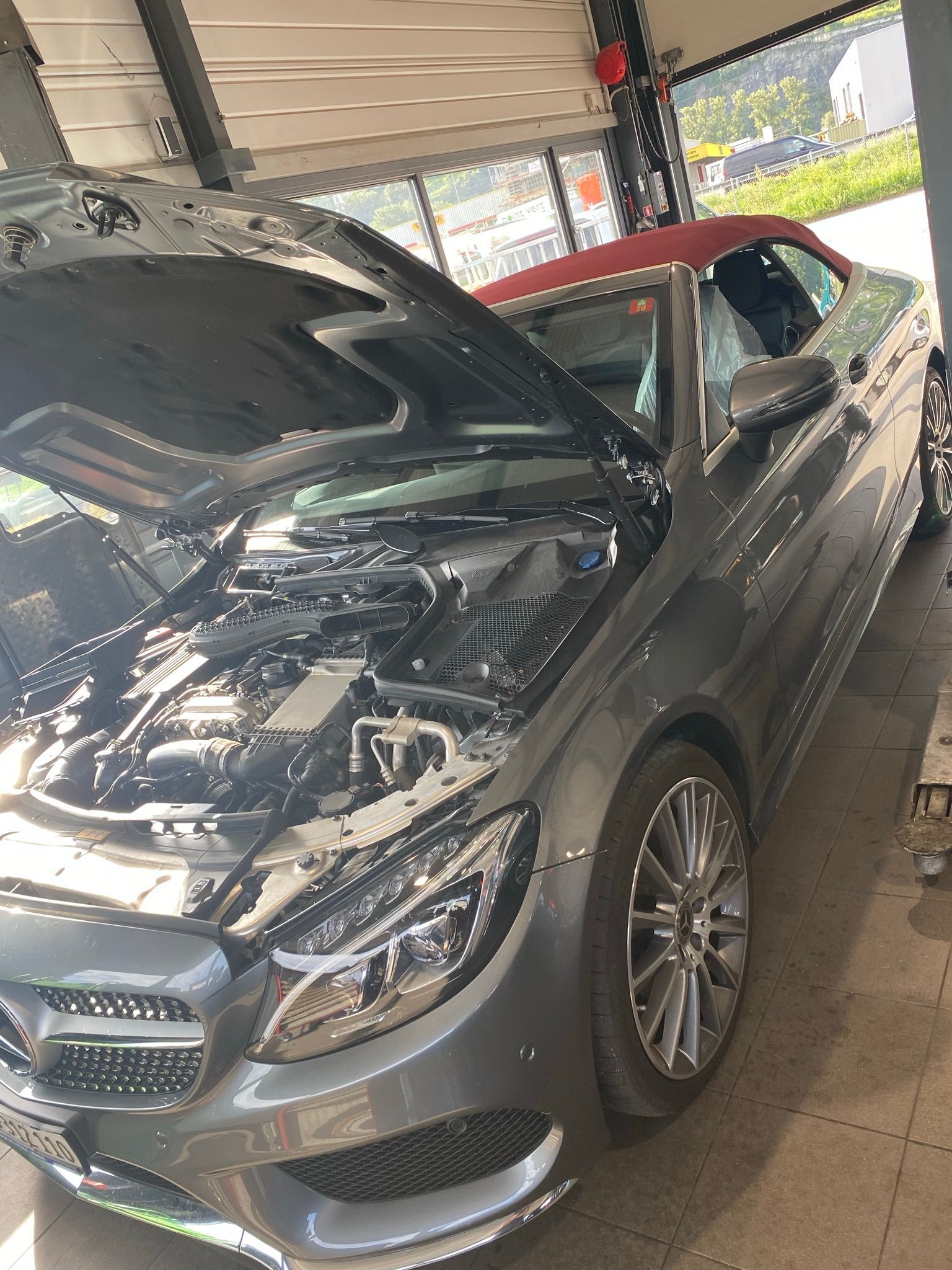 Une voiture avec le capot relevé est garée dans un garage.