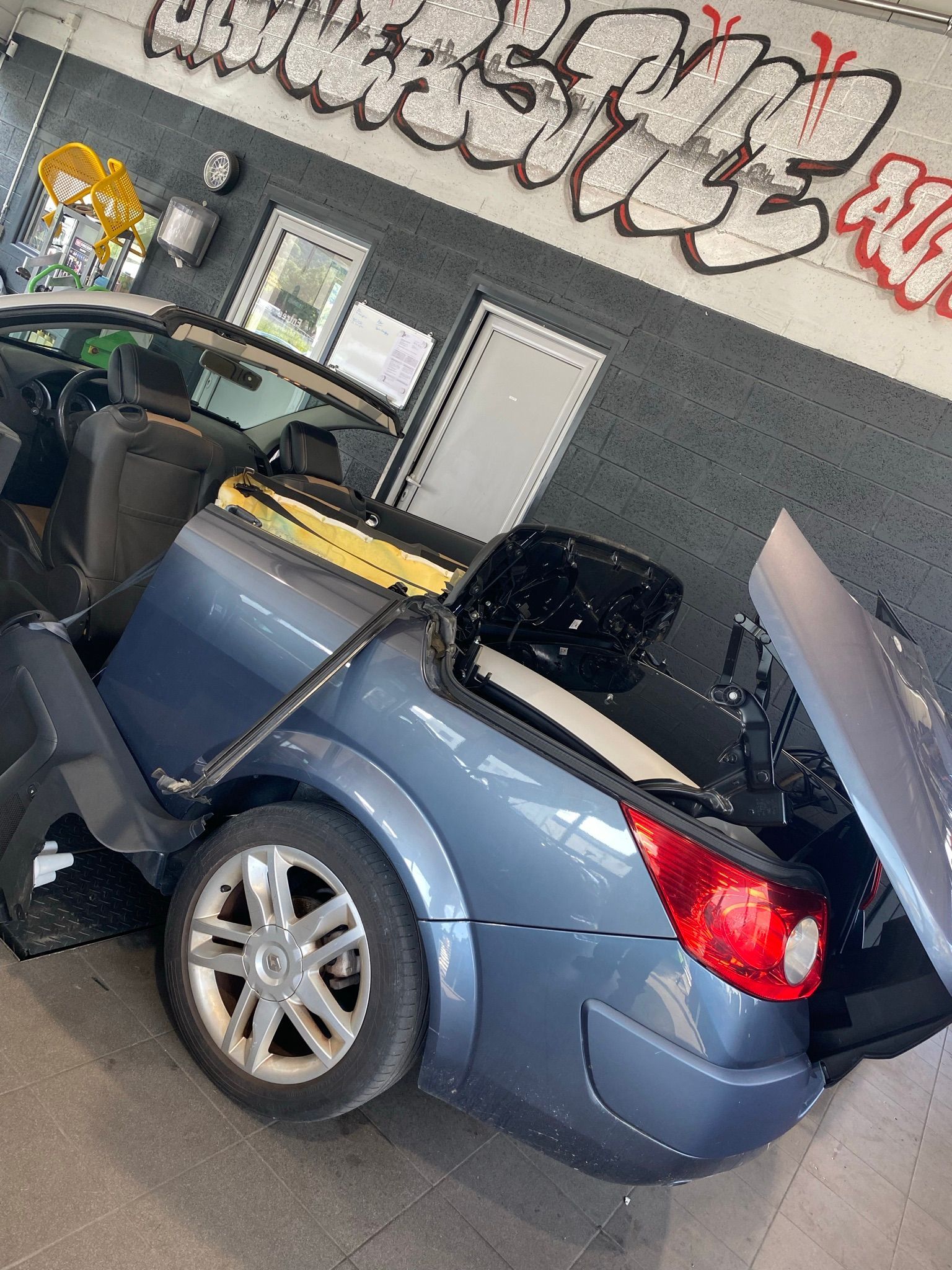 Une voiture bleue avec le coffre ouvert est garée dans un garage.