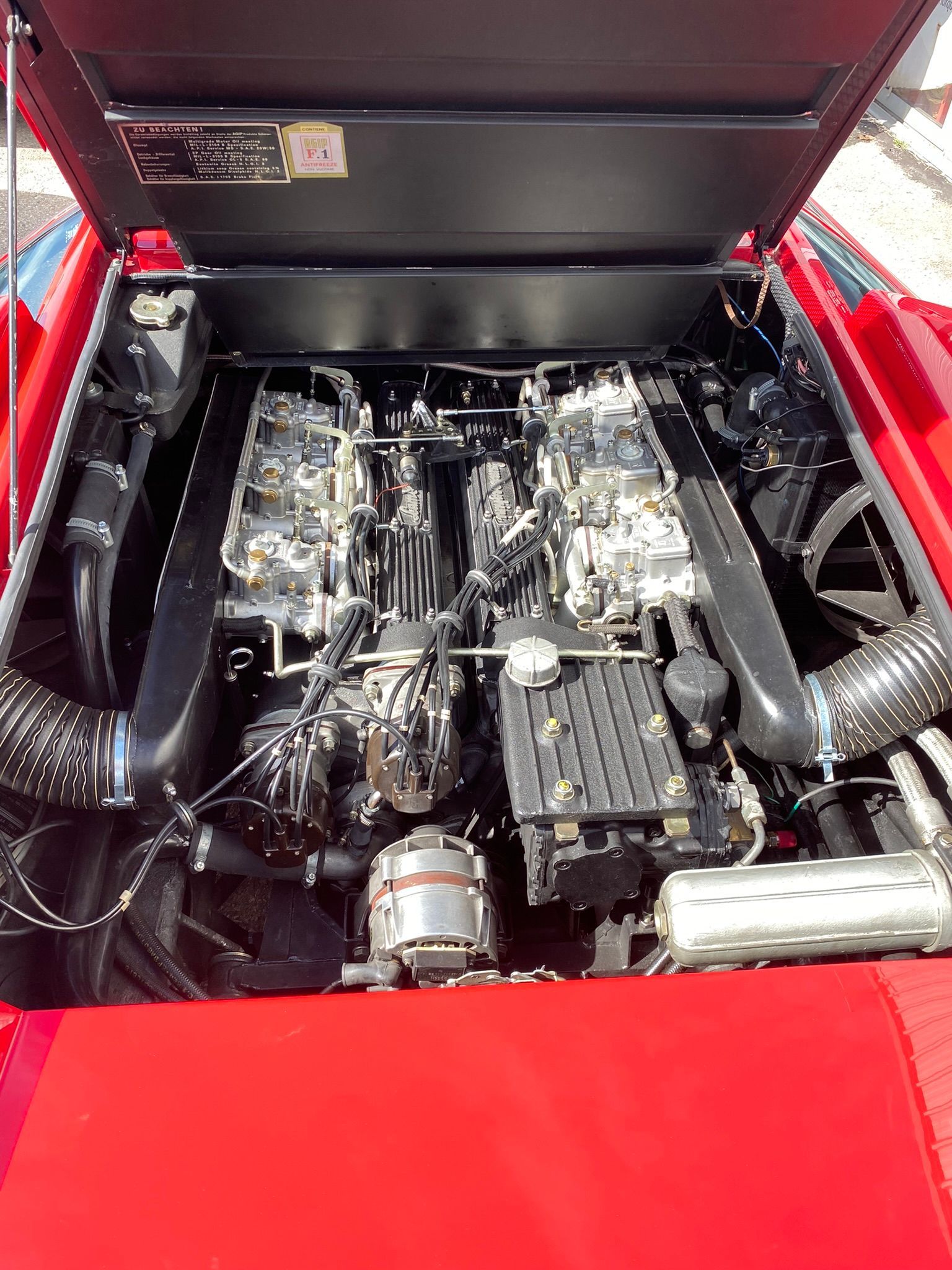 Le moteur d’une voiture de sport rouge avec le capot ouvert.