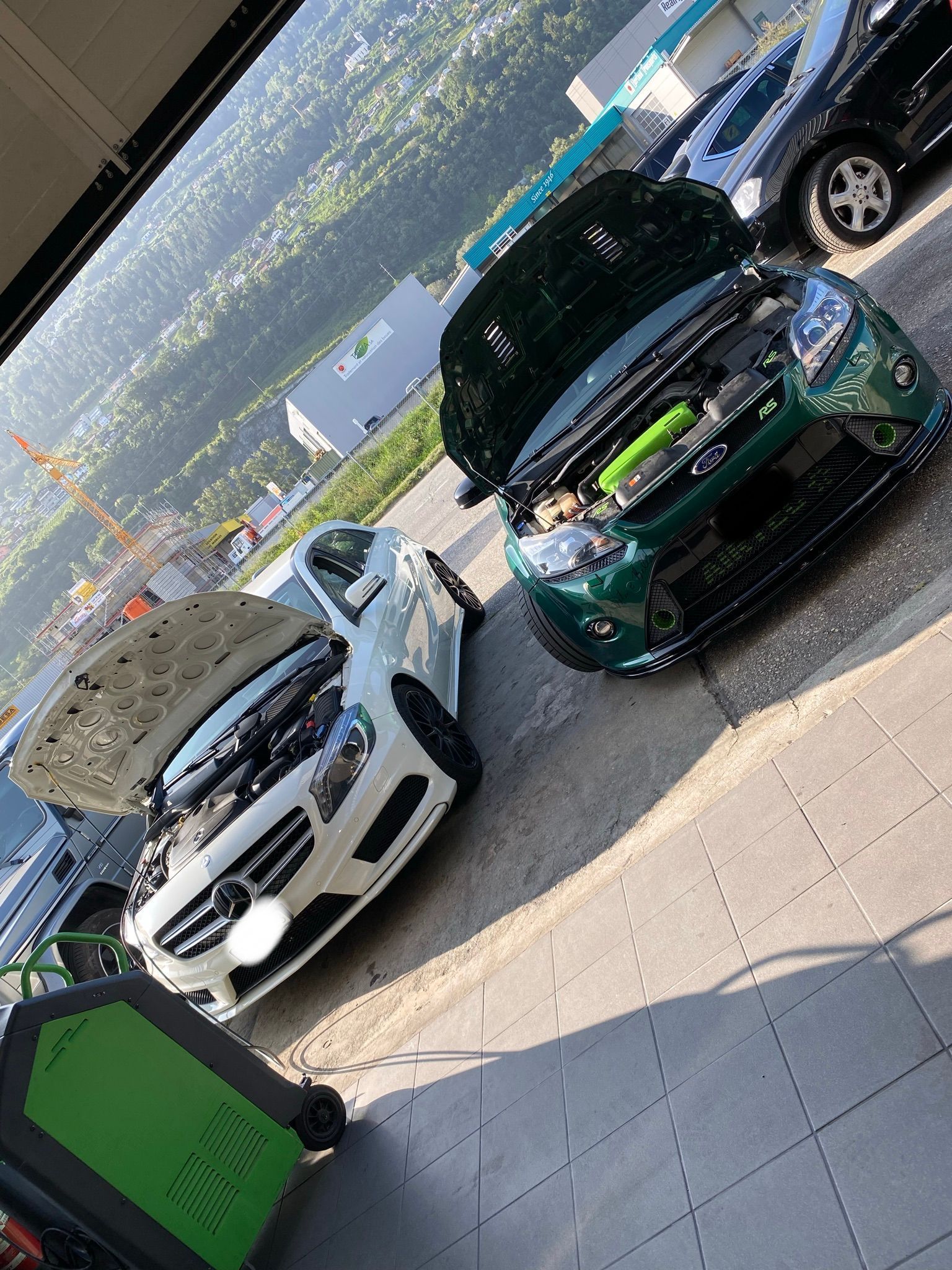 Deux voitures sont garées l’une à côté de l’autre, le capot ouvert.