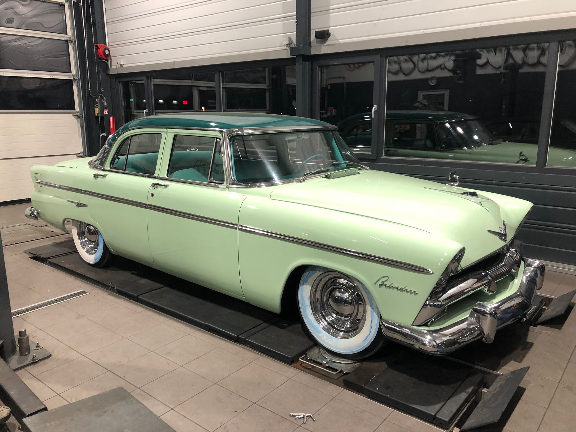 Une voiture verte est garée sur un ascenseur dans un garage.