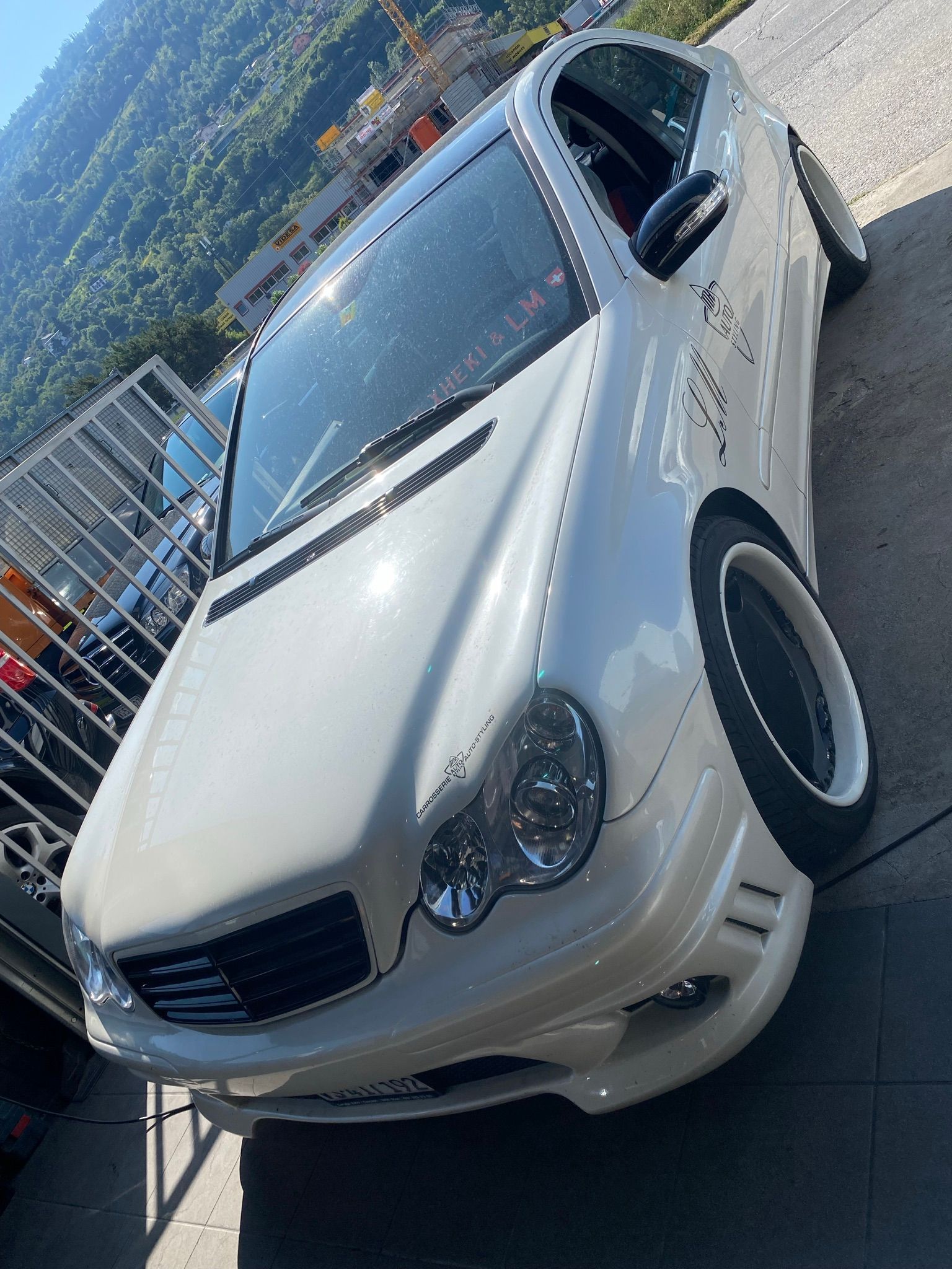 Une voiture blanche est garée sur le bord de la route