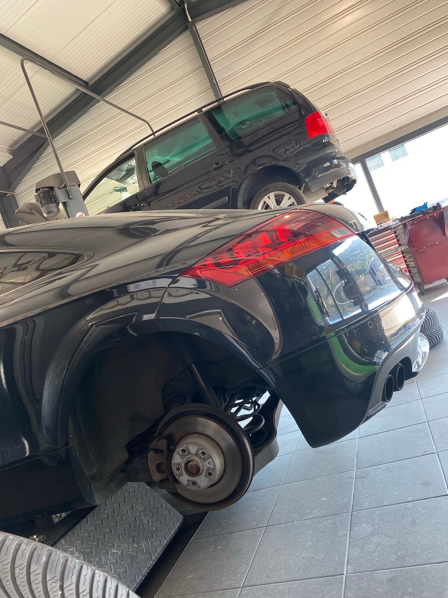 Une voiture avec une roue cassée est assise sur un ascenseur dans un garage.