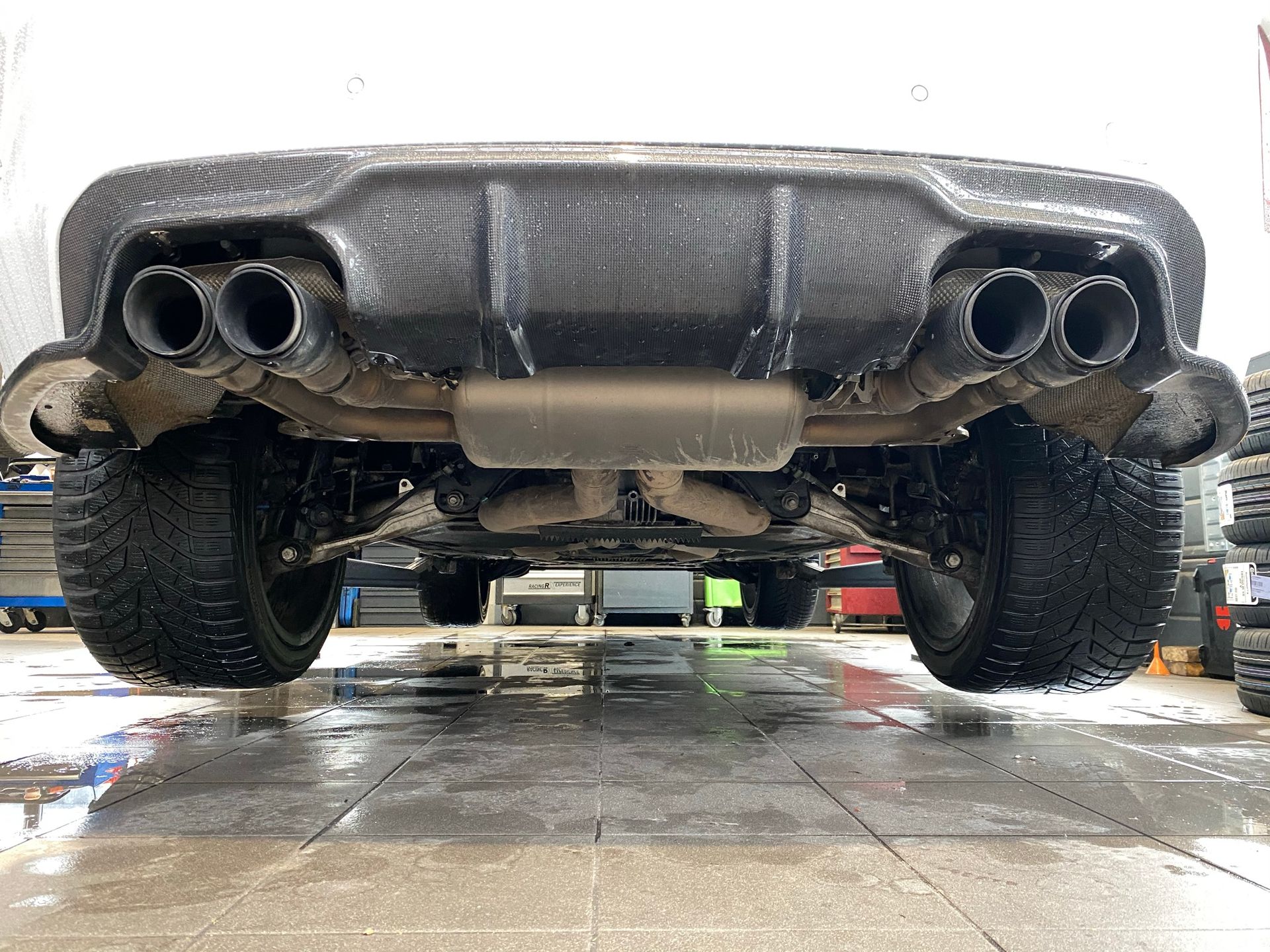 Une voiture blanche est garée sous un sol carrelé dans un garage.