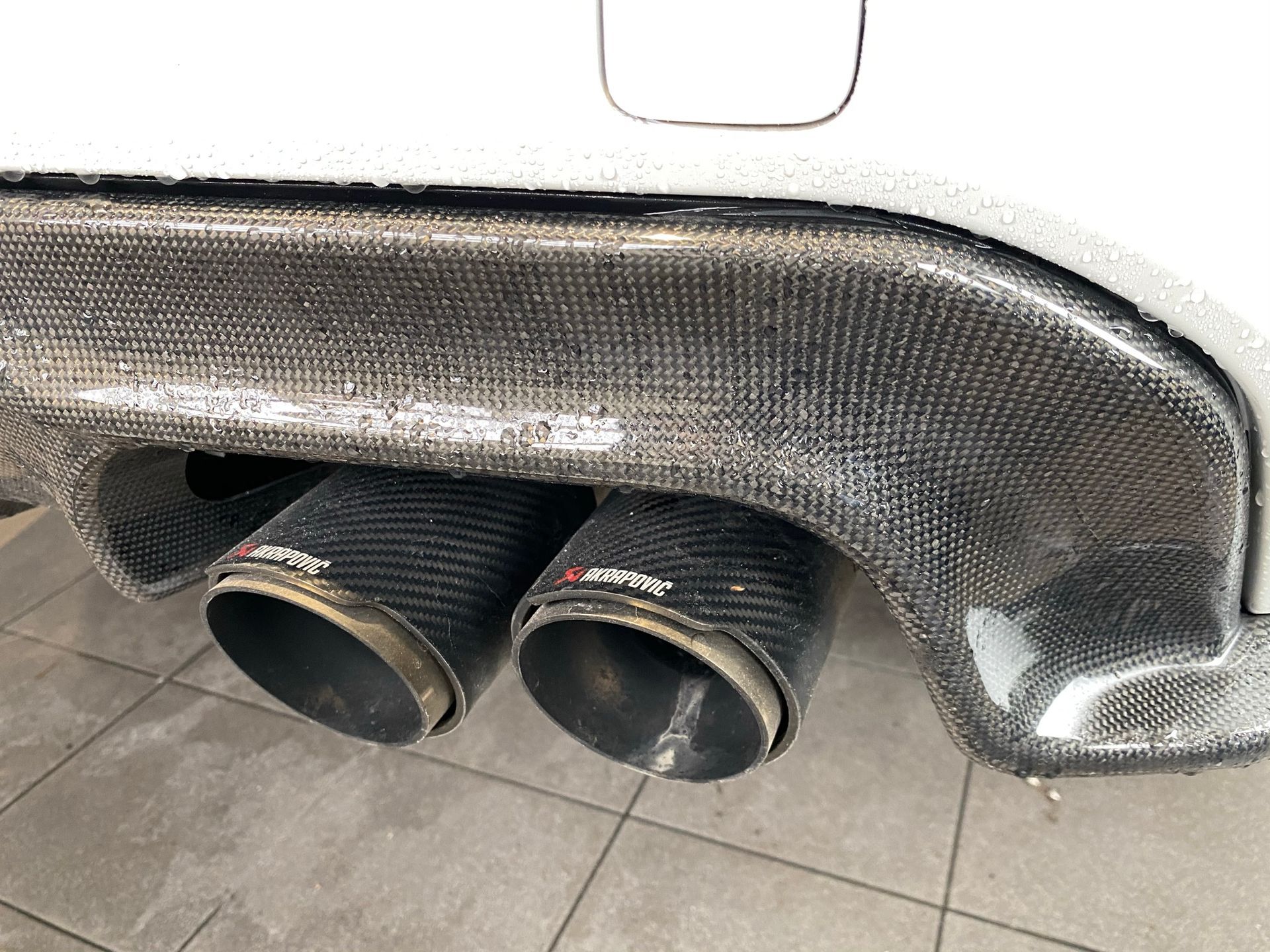 Un gros plan d'un tuyau d'échappement de voiture sur un sol carrelé.