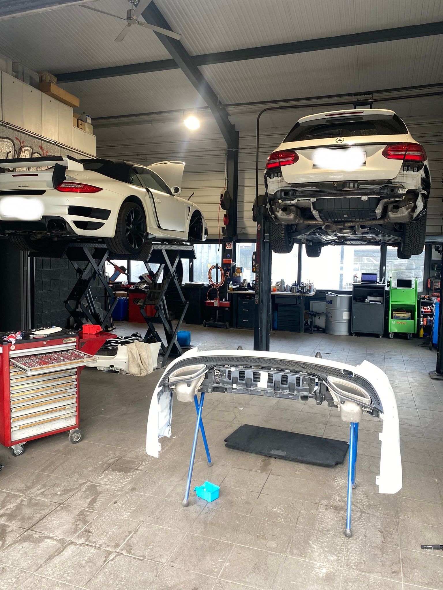 Deux voitures sont posées sur un ascenseur dans un garage.