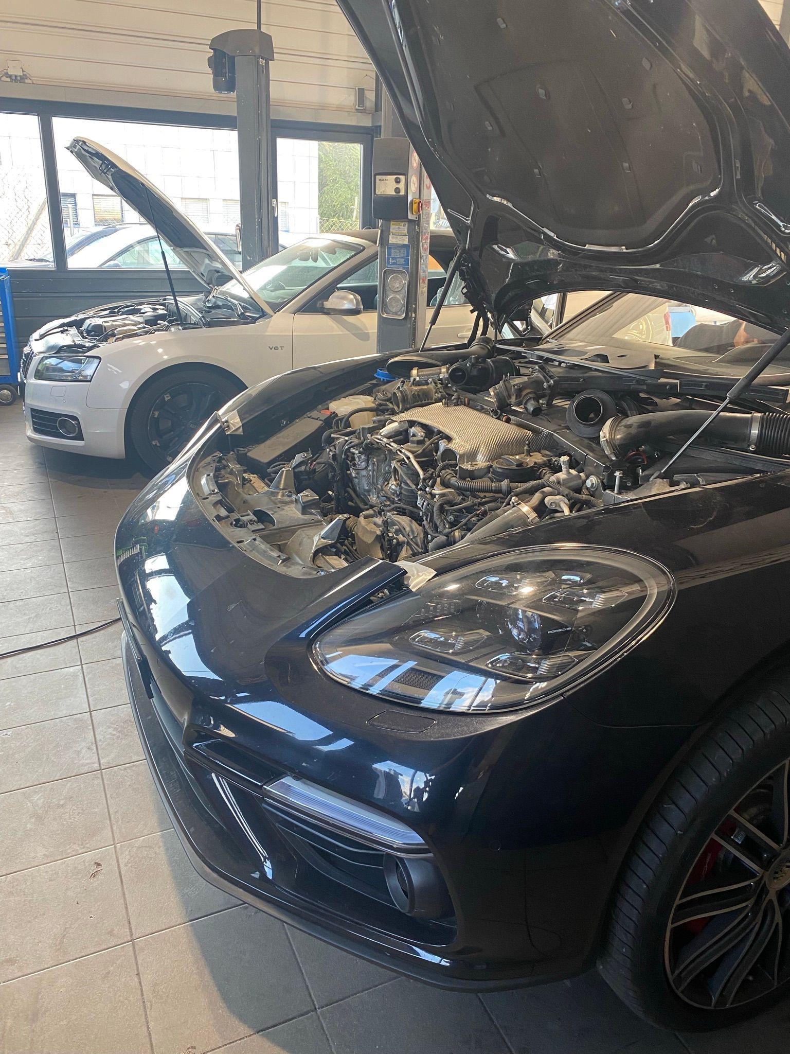 Une voiture noire avec son capot ouvert dans un garage.