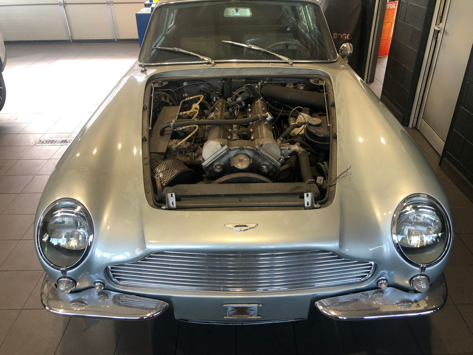 Une voiture argentée avec le capot ouvert et le moteur exposé