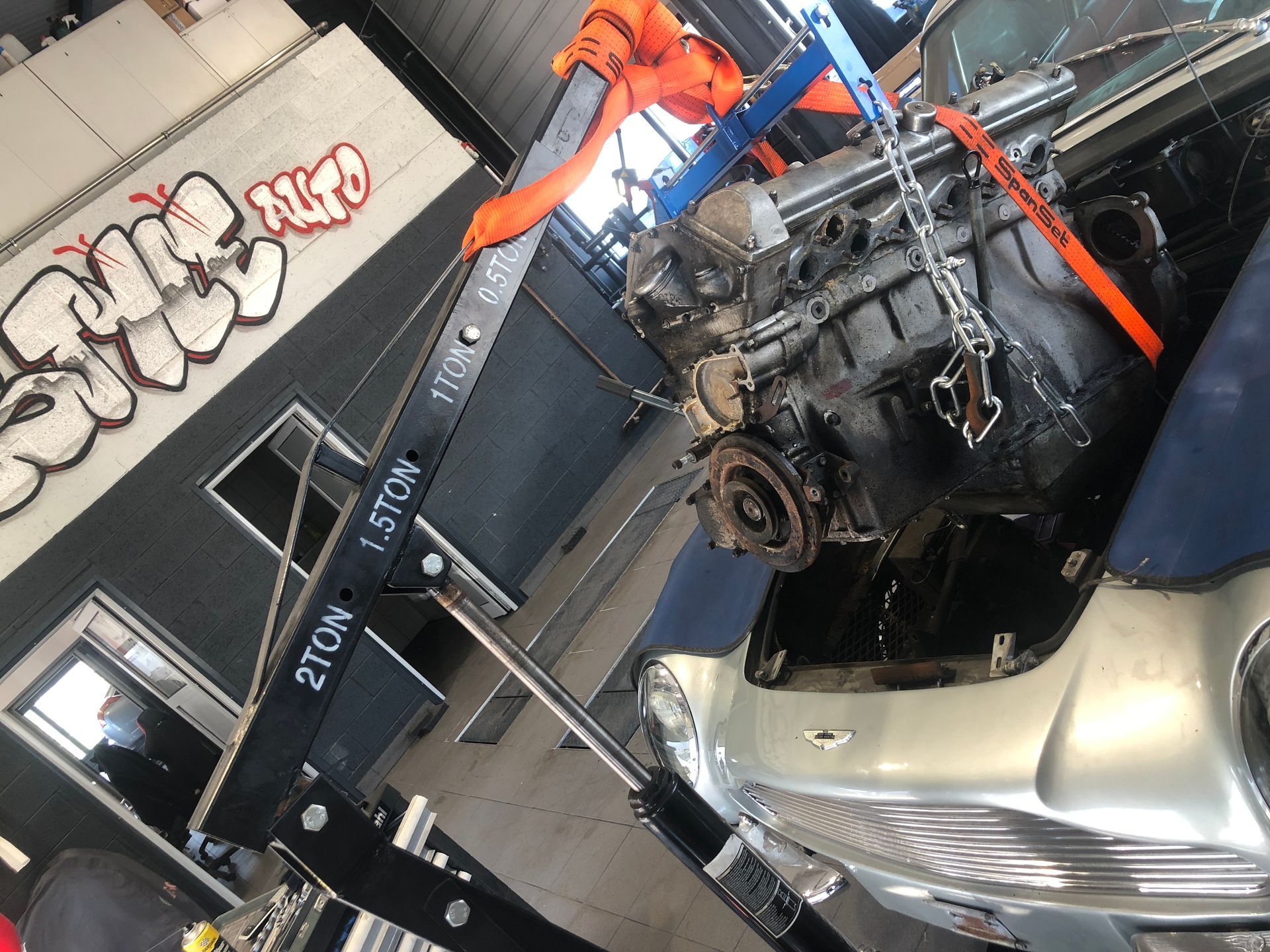Un moteur de voiture est soulevé par une grue dans un garage
