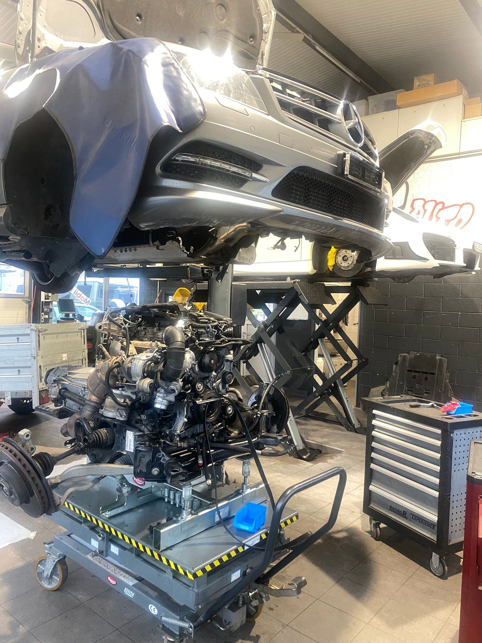 Une voiture est en travaux dans un garage.