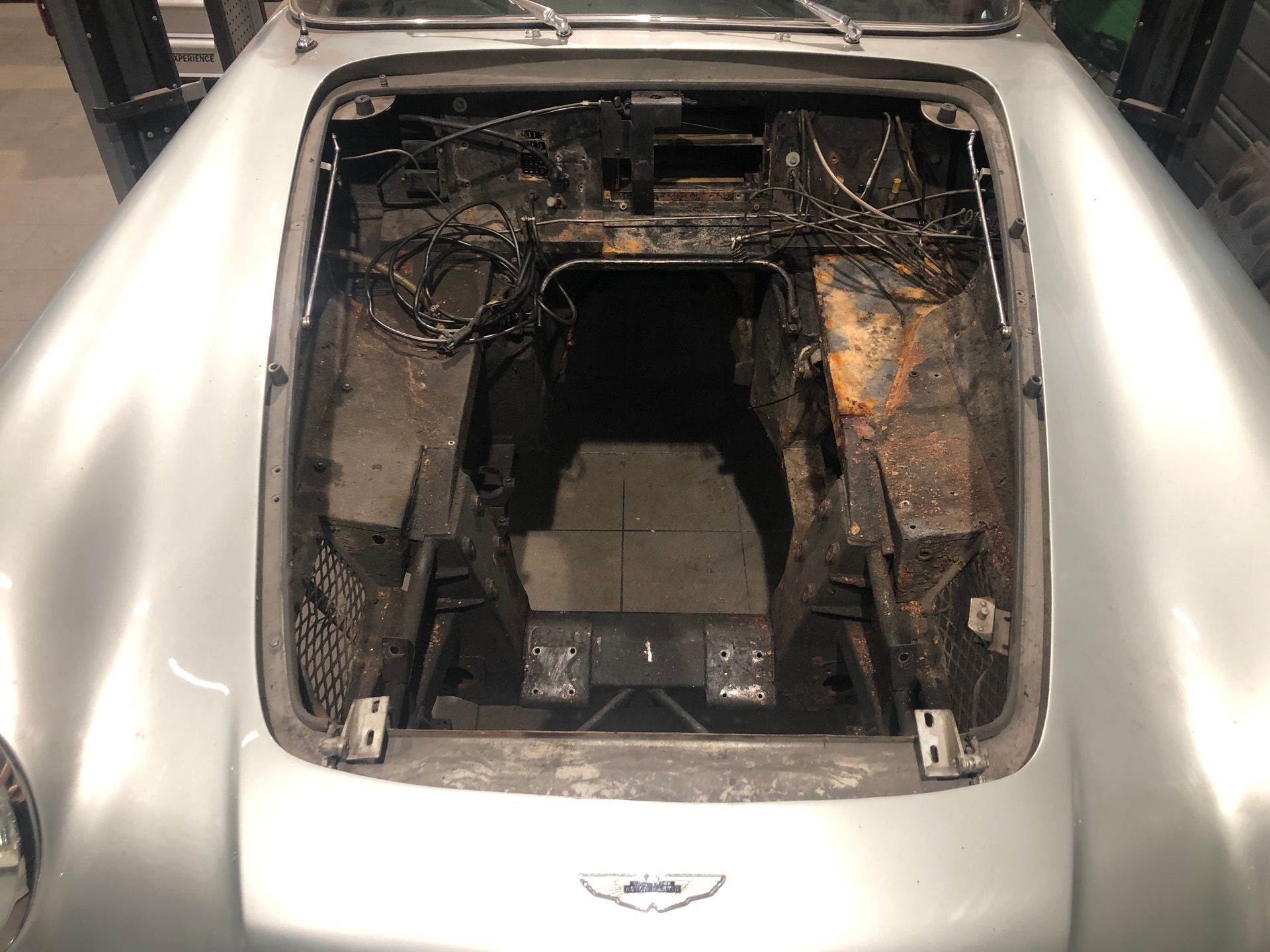 Le capot d'une voiture argentée est ouvert et le moteur est visible.