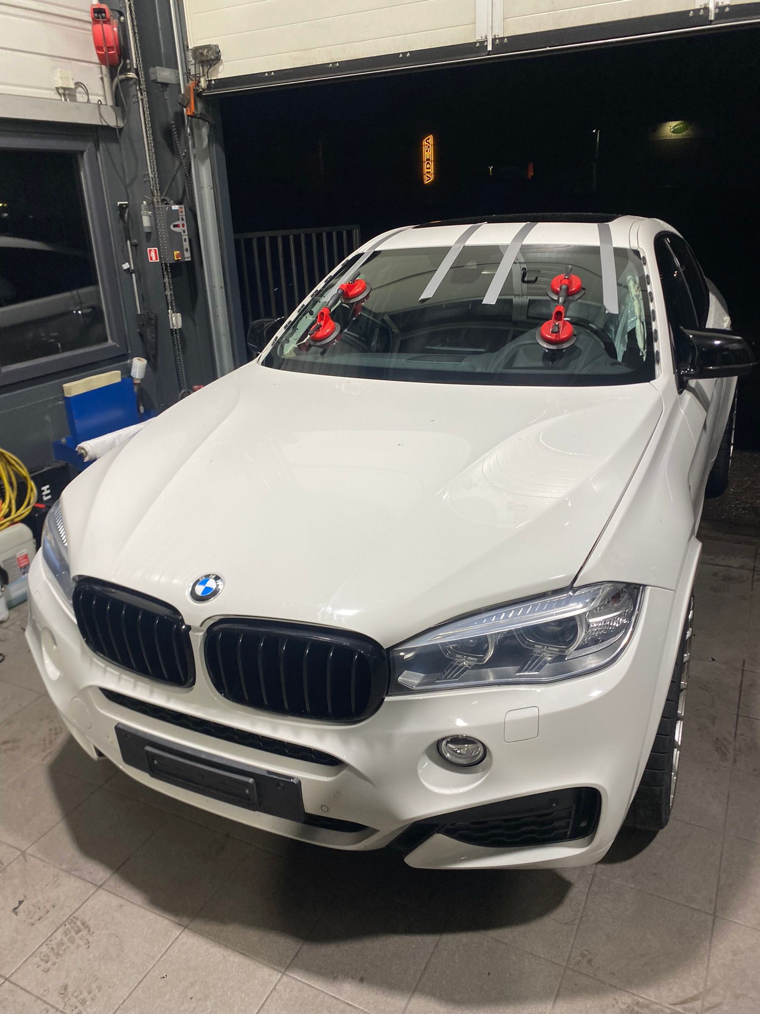 Une BMW X6 blanche est garée dans un garage.