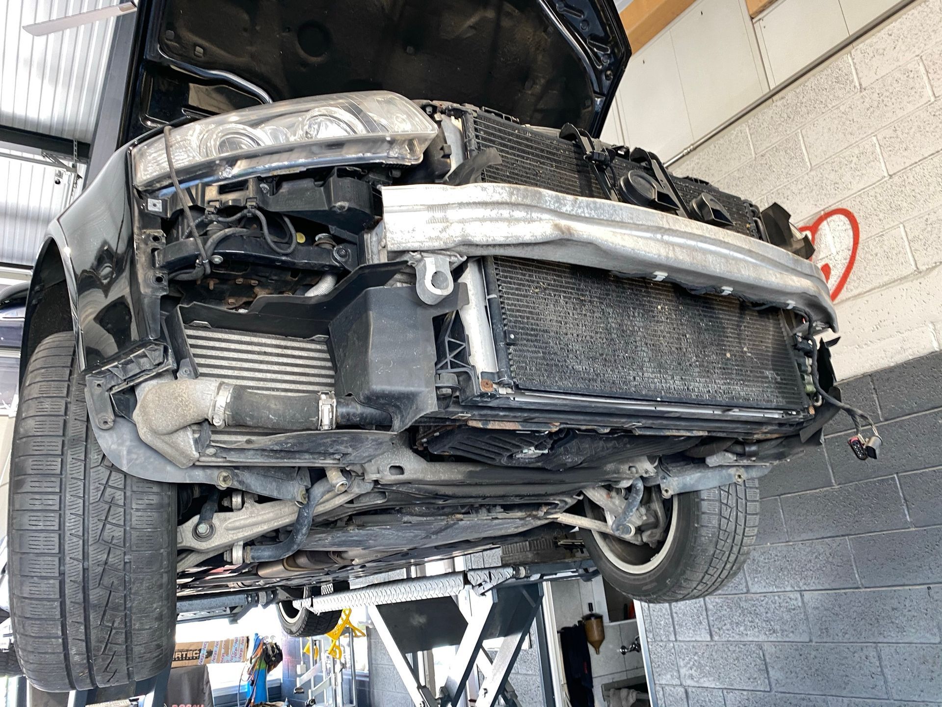 Une voiture avec le capot relevé est posée sur un ascenseur dans un garage.