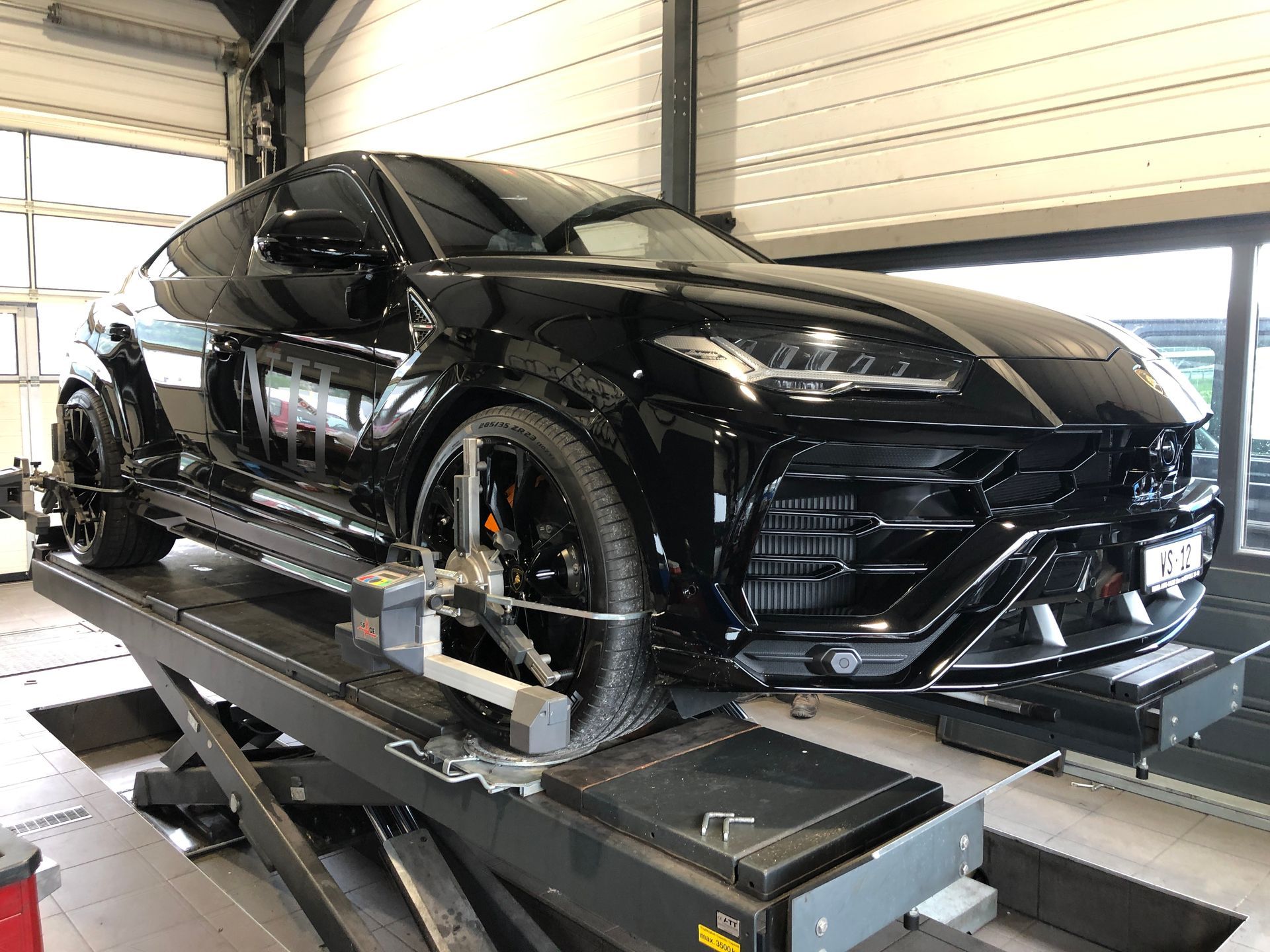 Un urus lamborghini noir est assis sur un ascenseur dans un garage.