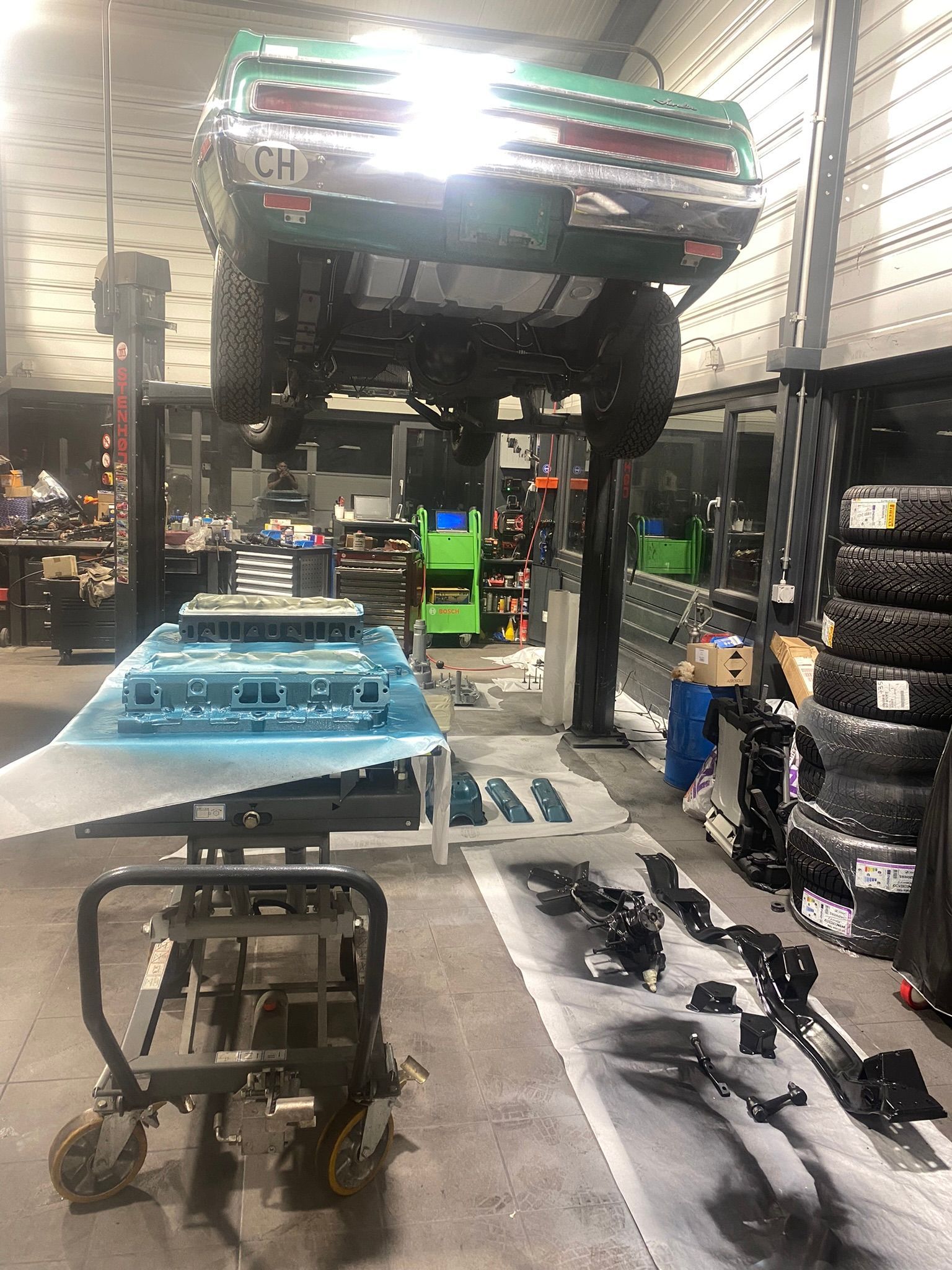 Une voiture verte est assise sur un ascenseur dans un garage.