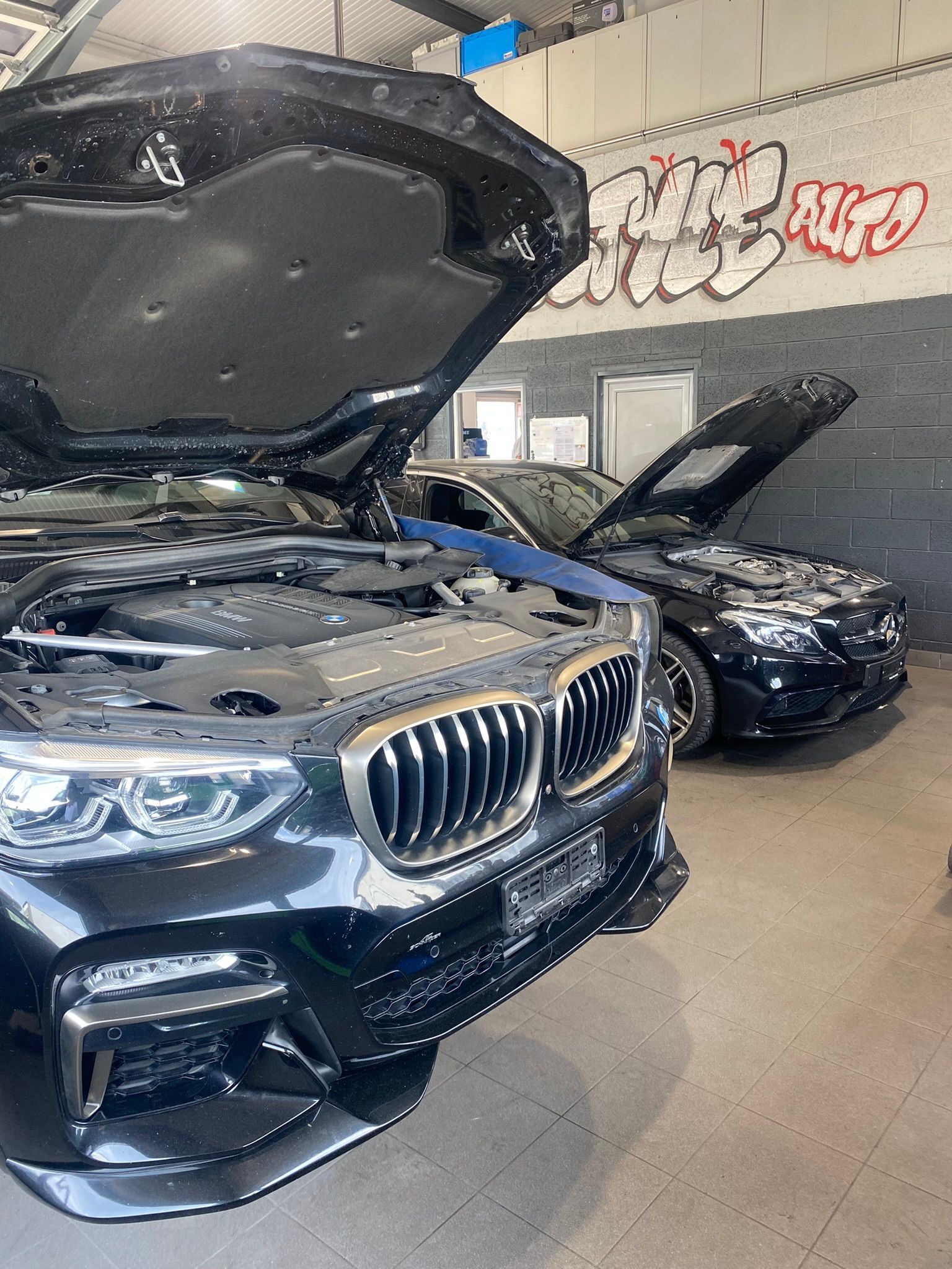Une BMW avec son capot ouvert est garée dans un garage.