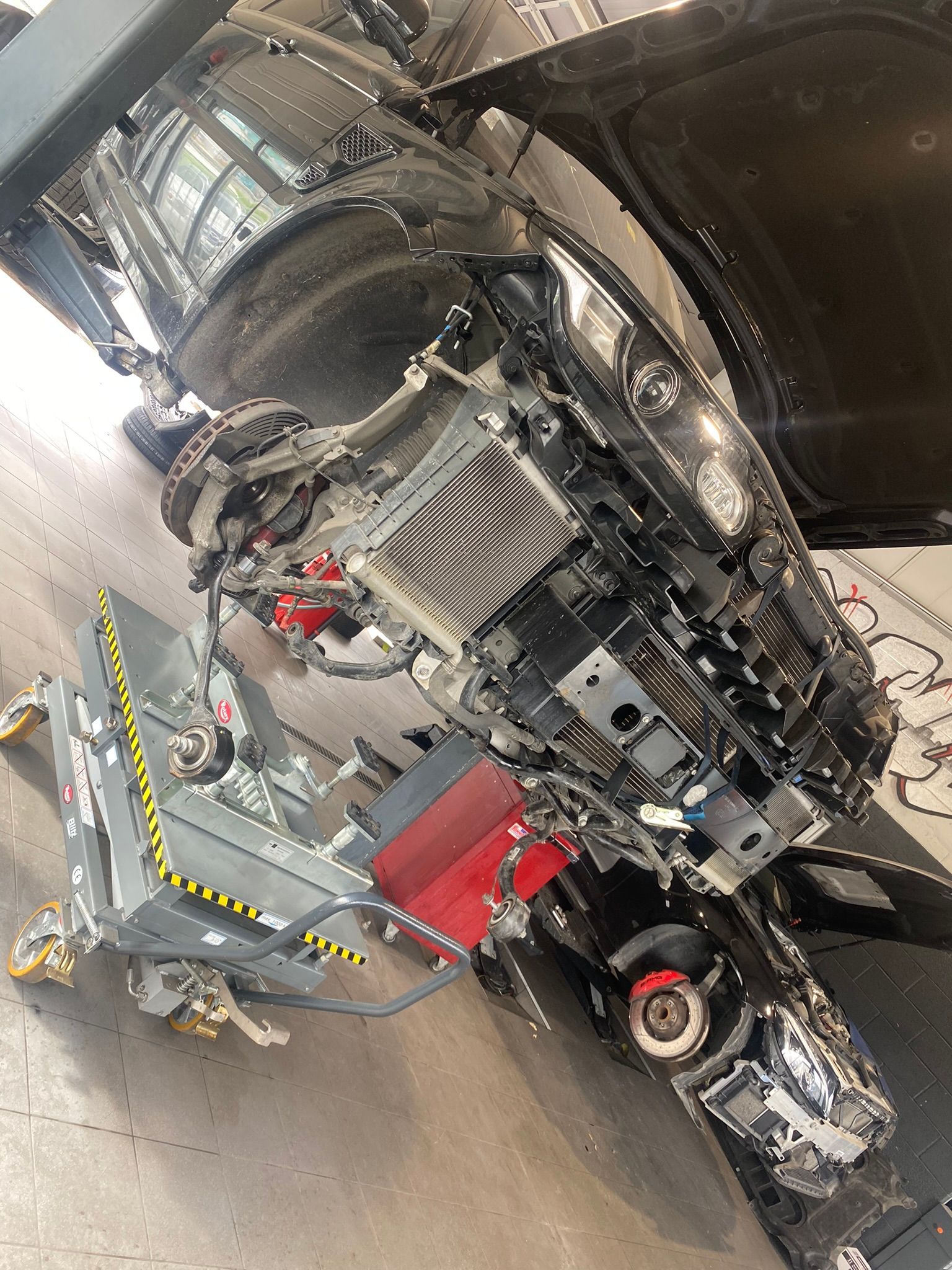 Une voiture est démontée dans un garage avec le capot ouvert.