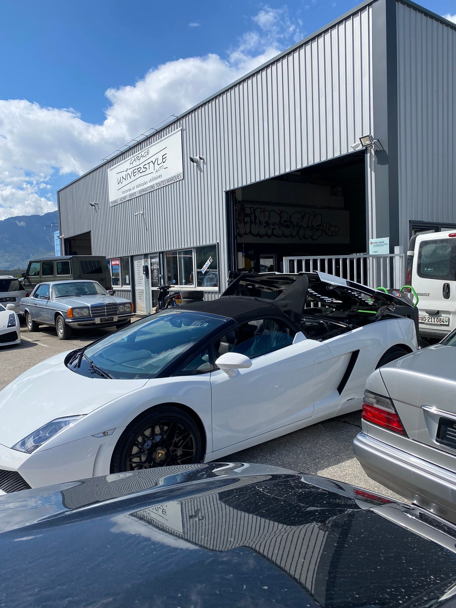 Une voiture de sport blanche est garée devant un immeuble.