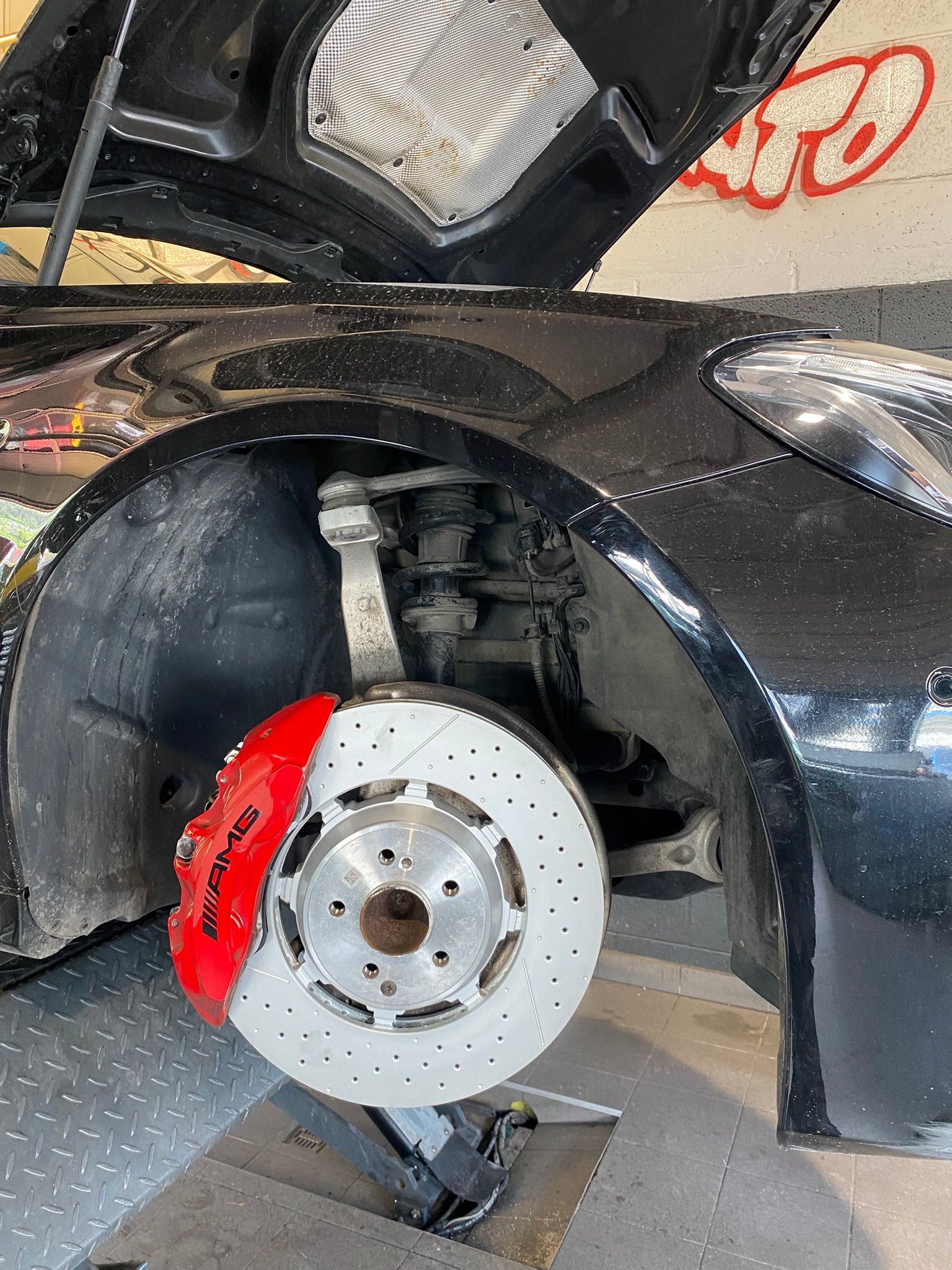 Une voiture noire avec un étrier de frein rouge est assise sur un ascenseur.