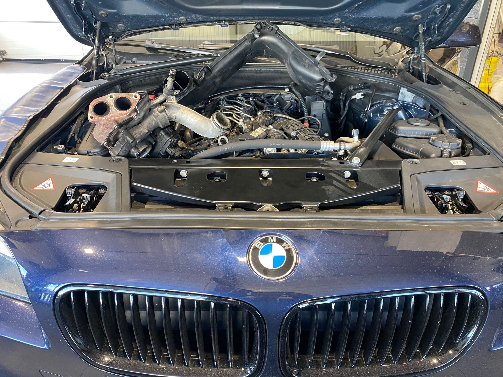 Le moteur d'une BMW est représenté avec le capot ouvert.