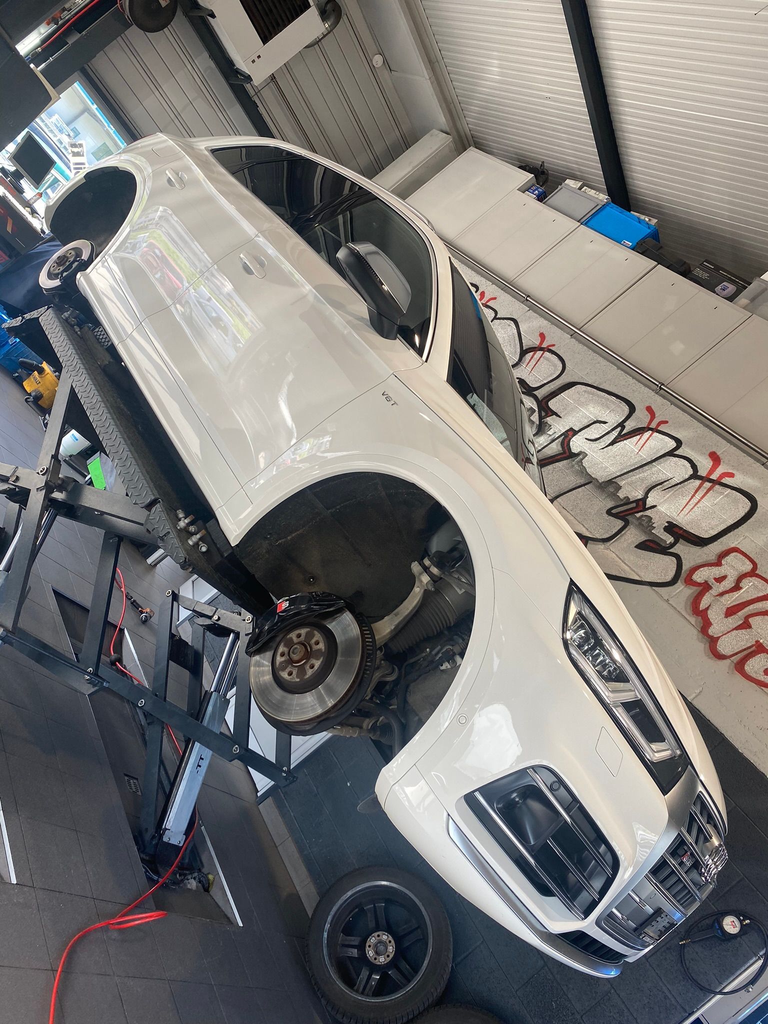 Une voiture blanche est en travaux dans un garage.