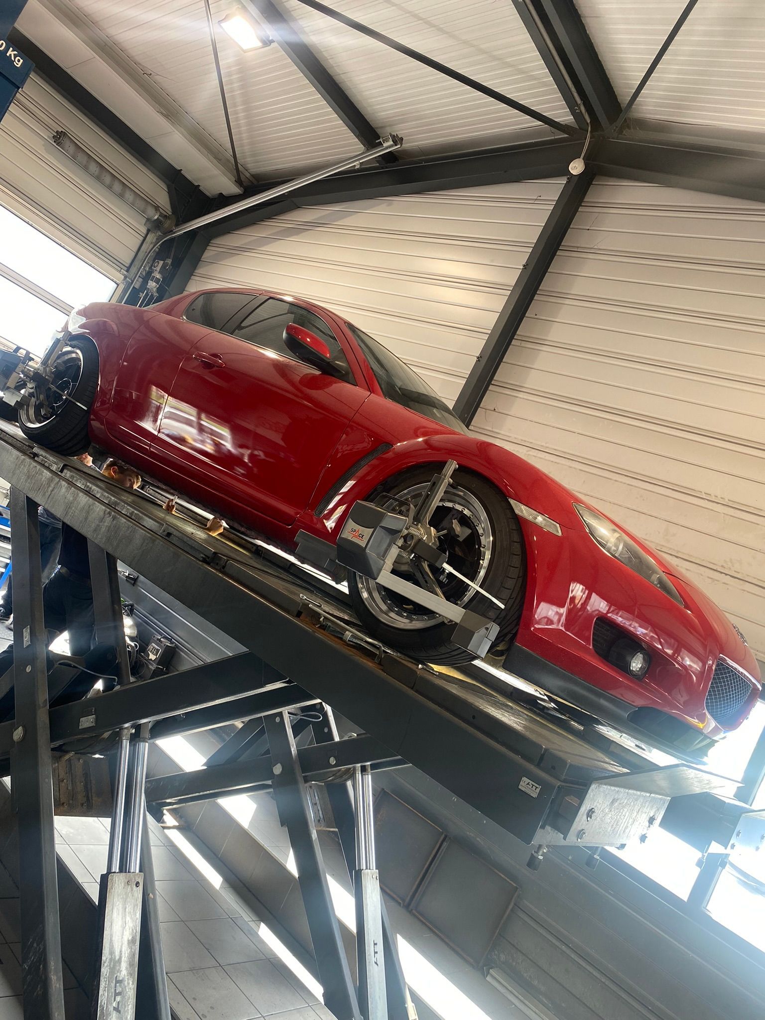 Une voiture rouge est assise au sommet d’une rampe dans un garage.