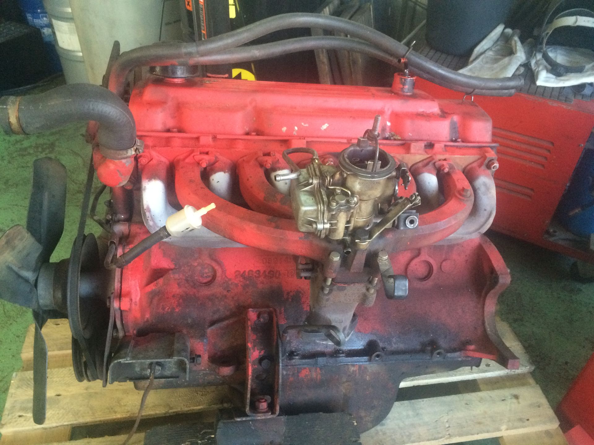 Un moteur rouge est posé sur une palette en bois.