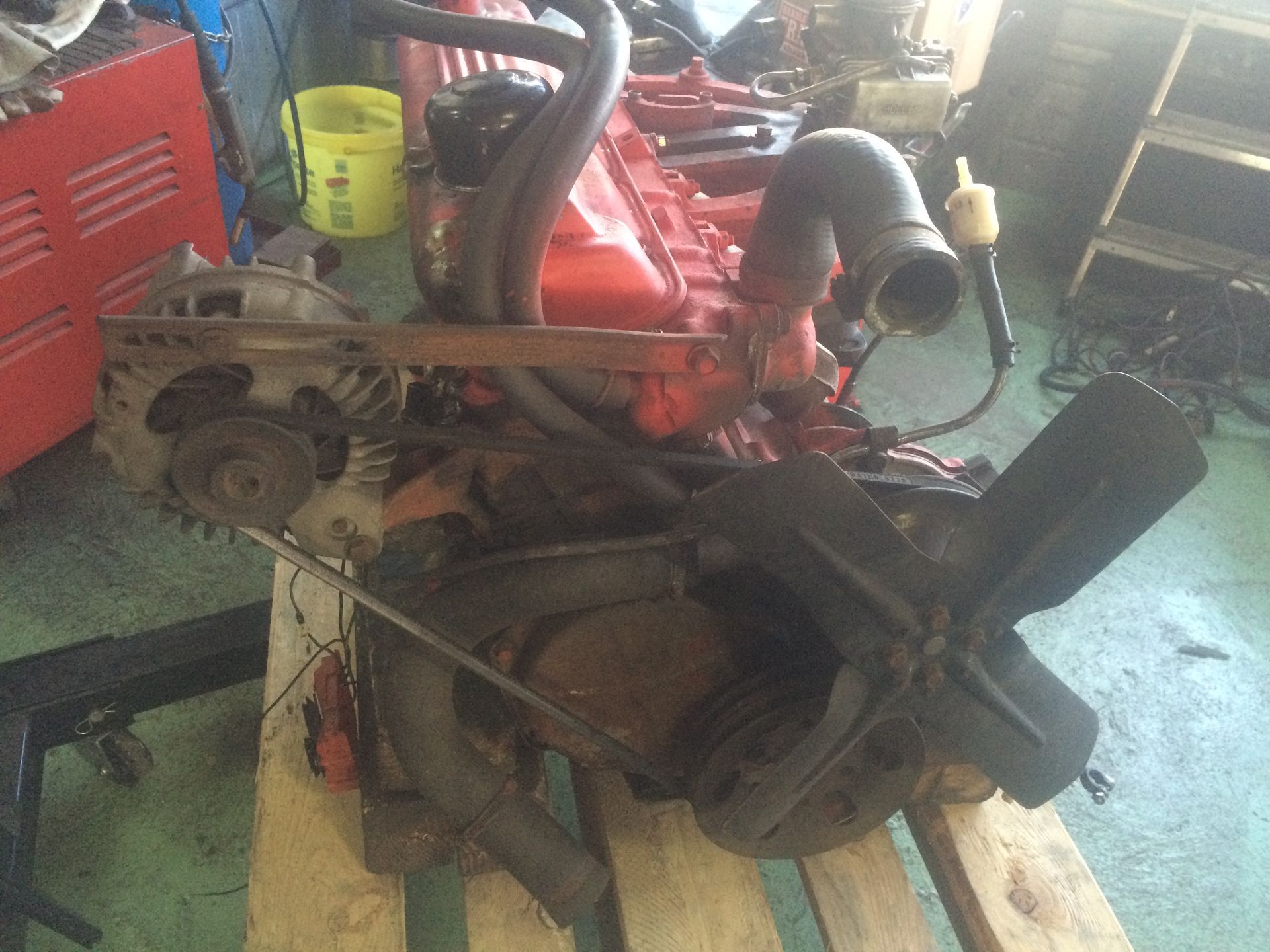 Un vieux moteur est posé sur une palette en bois dans un garage.