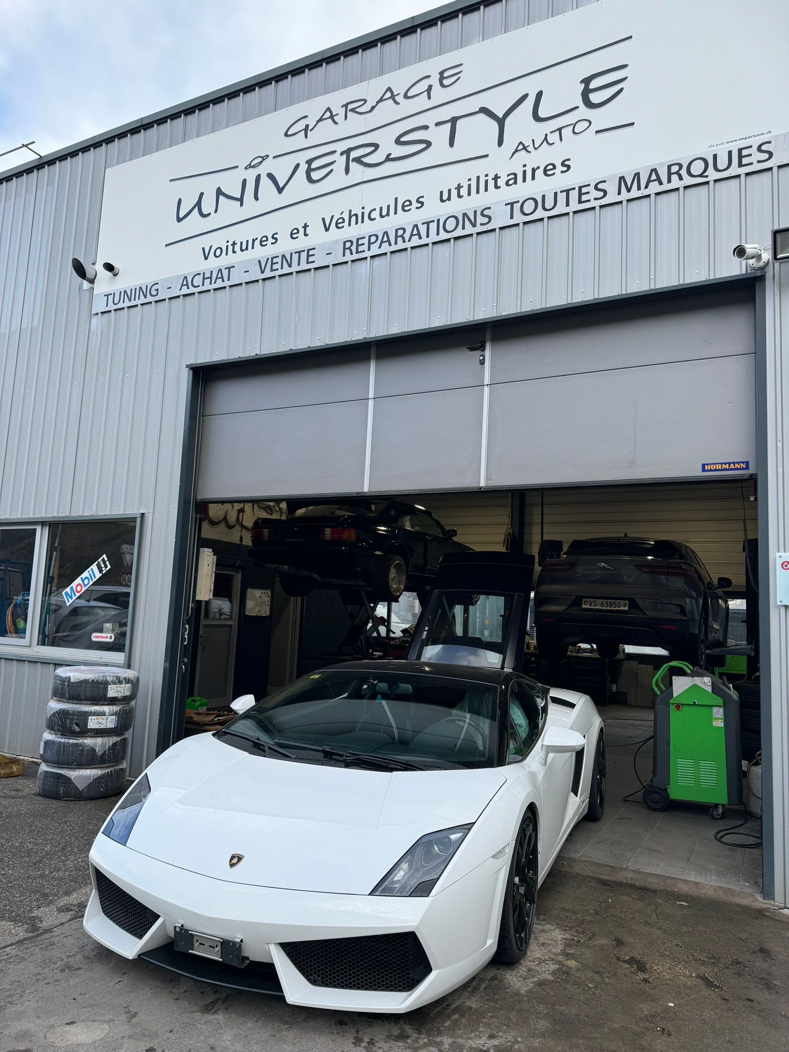 Une voiture de sport blanche est garée devant un garage.