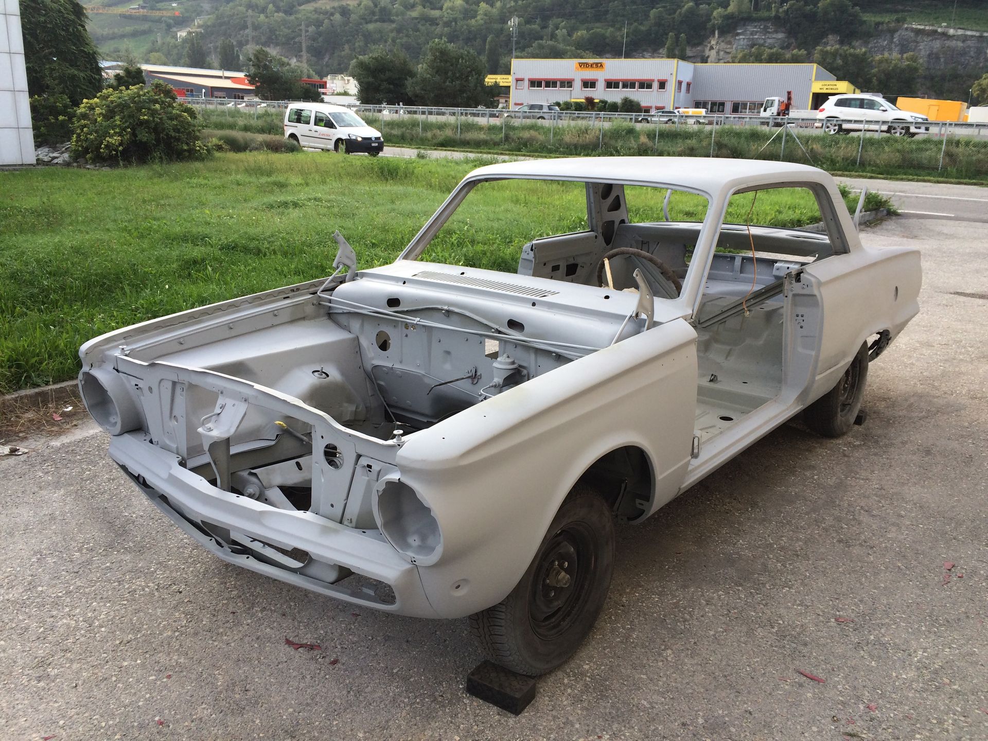 Une voiture blanche sans capot est garée sur le bord de la route