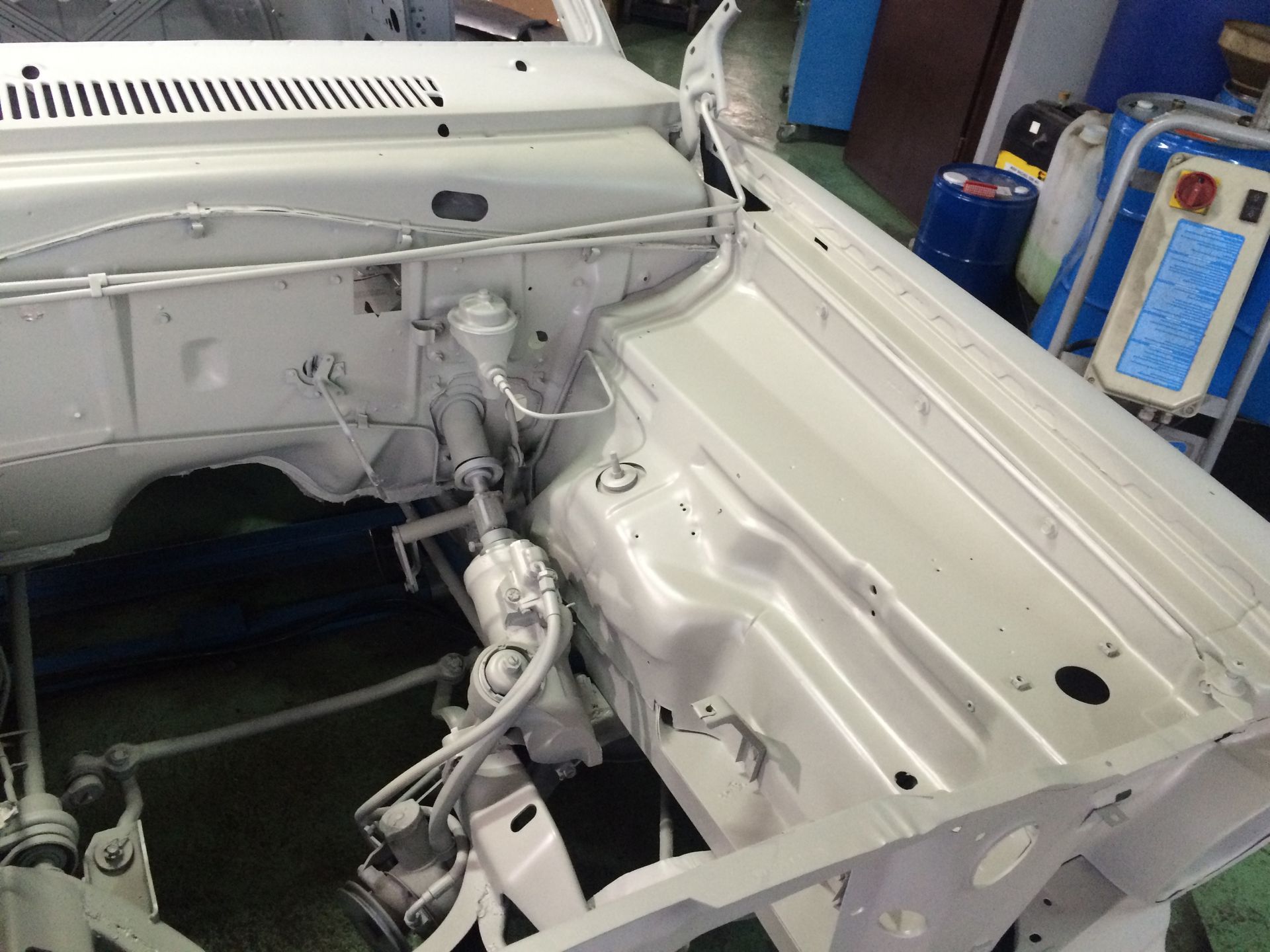 Une voiture blanche est en train d'être peinte dans un garage.