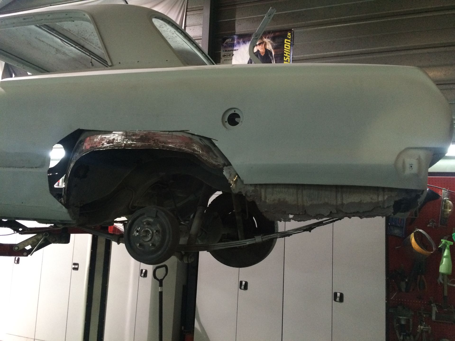 Une voiture blanche est assise sur un ascenseur dans un garage