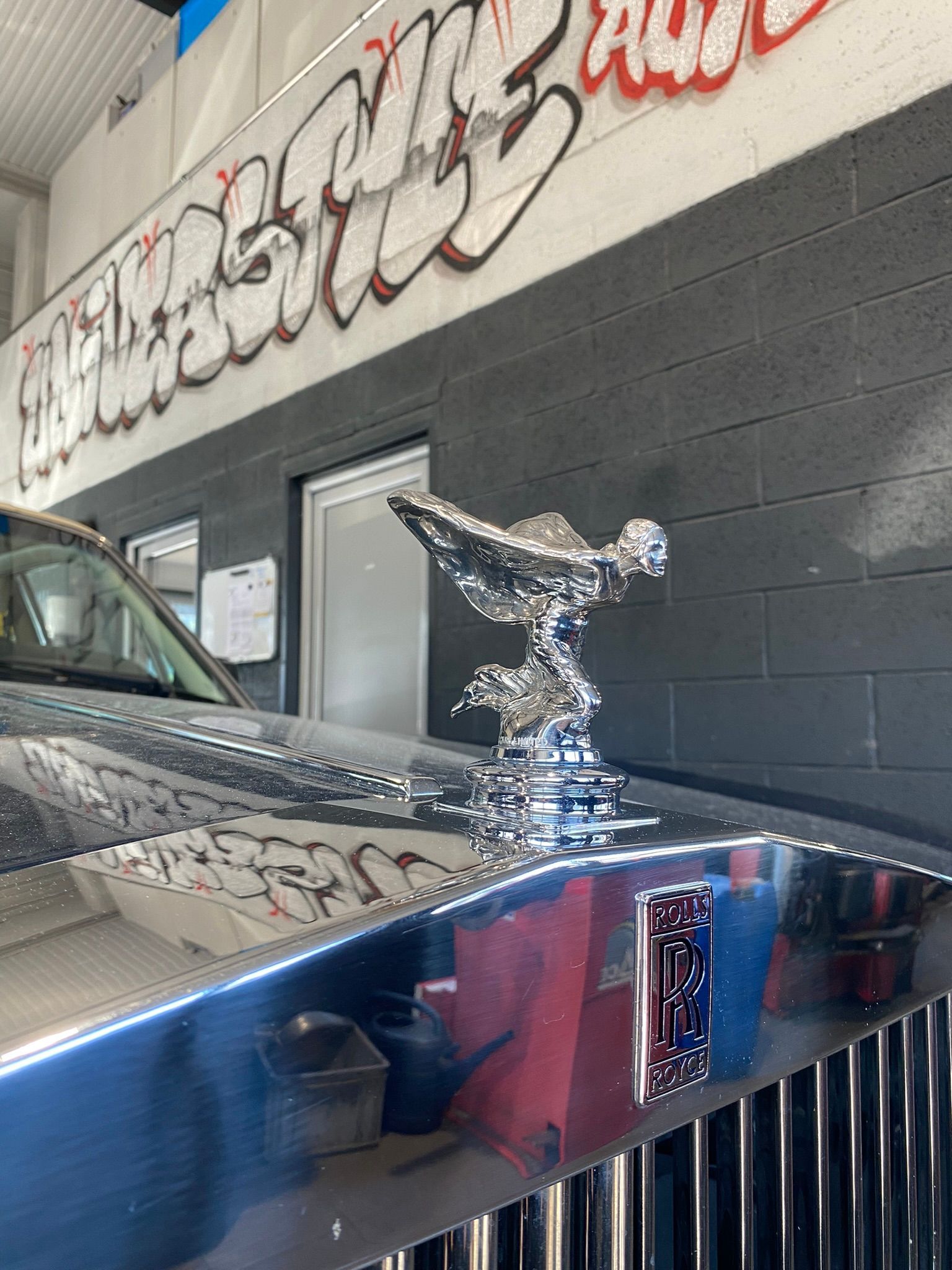 Un gros plan d'un ornement de capot sur une voiture dans un garage.