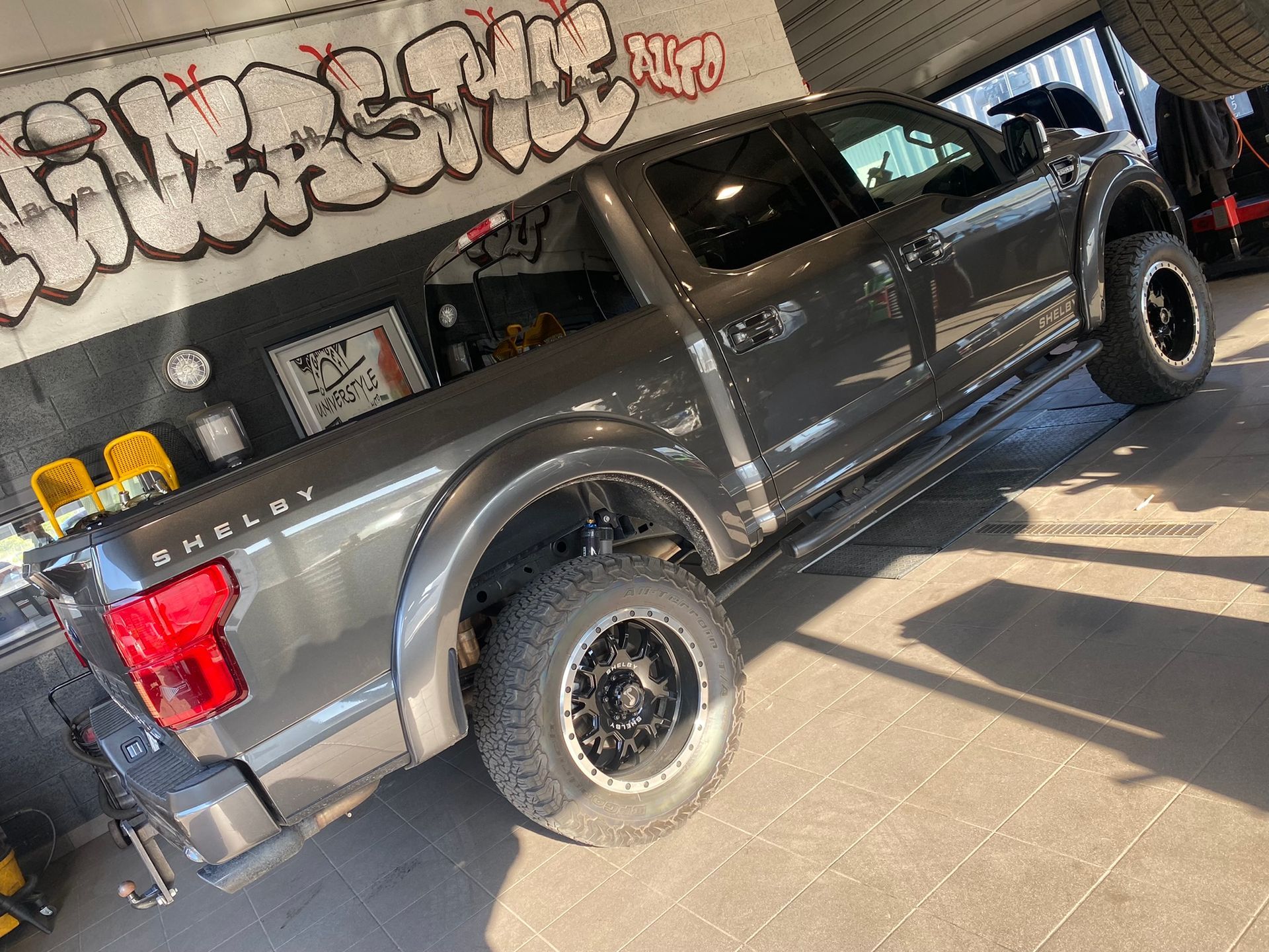 Un camion gris est garé dans un garage avec des graffitis sur le mur.