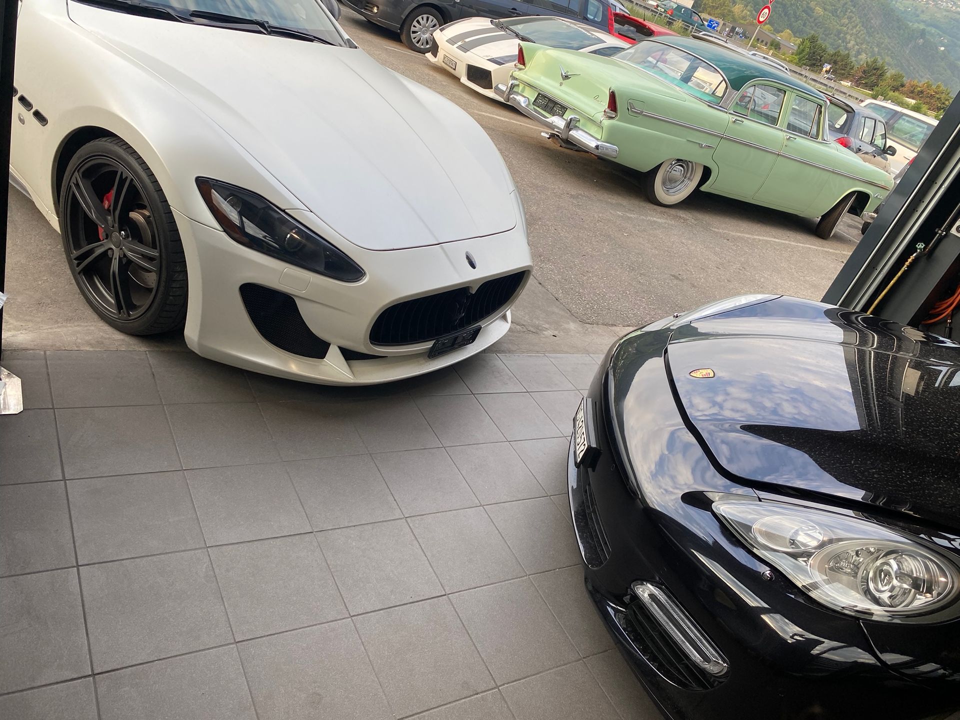 Une voiture blanche est garée à côté d’une voiture noire dans un parking.