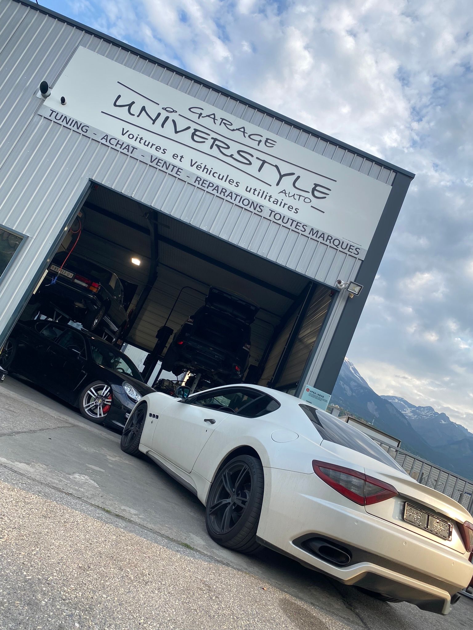 Une voiture de sport blanche est garée devant un immeuble.