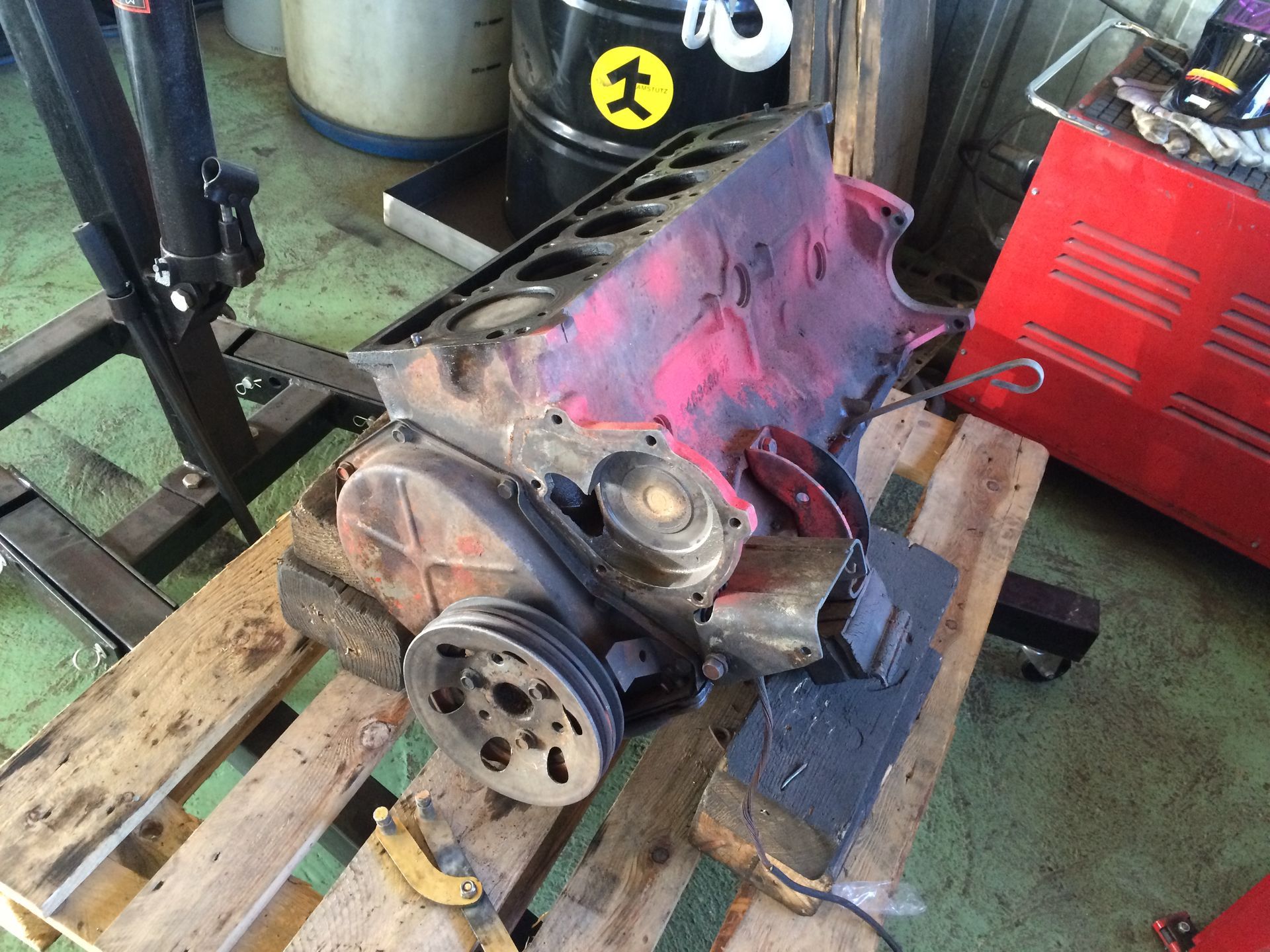 Un moteur est posé sur une palette en bois dans un garage.