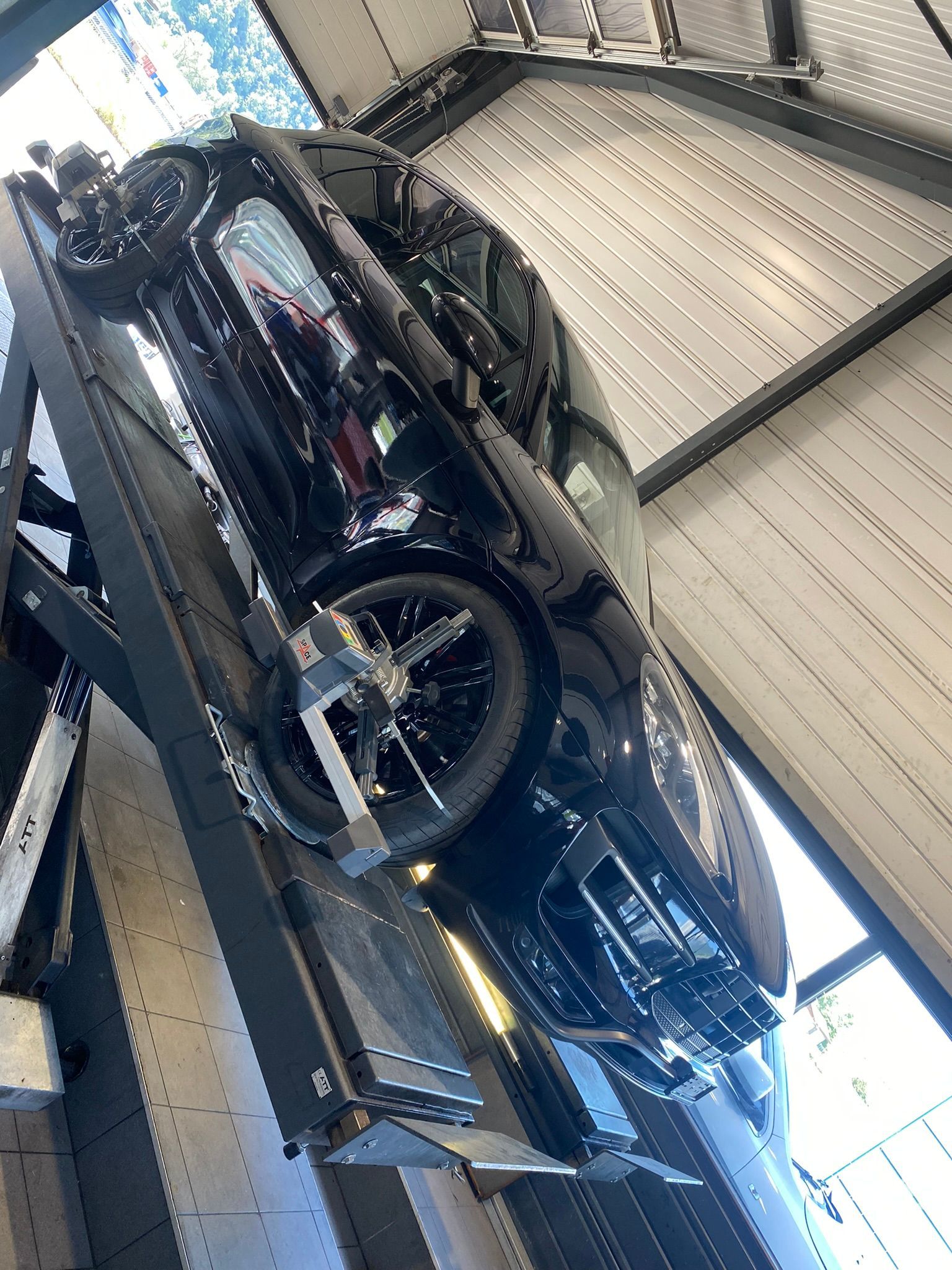 Une voiture noire est assise sur un ascenseur dans un garage.